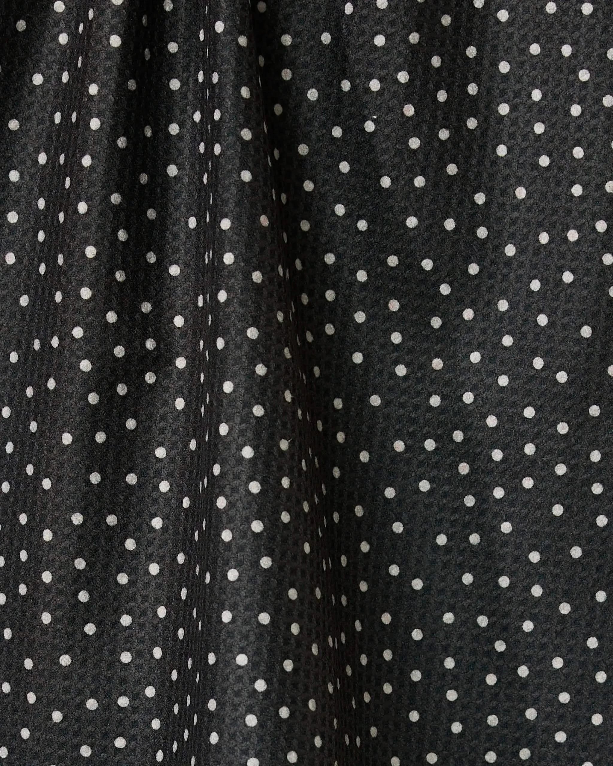 Close-up of the Geometry Sweet Canes tea towel, featuring quick-drying black fabric with evenly spaced white polka dots, soft folds, and a slight sheen that creates subtle texture and shadows.
