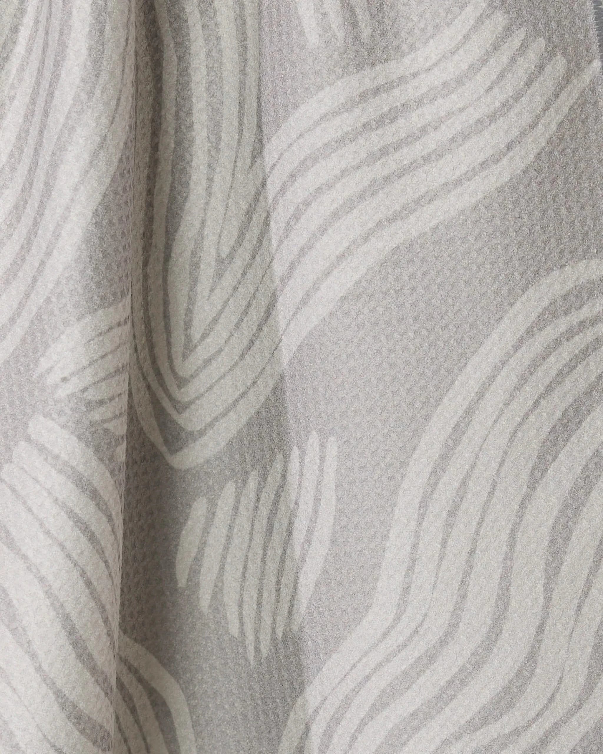 Close-up of Geometrys Stone tea towel in light gray textured fabric with wavy white lines, creating a soft, flowing look. The fabric is draped for added depth and subtle shadow. Quick-drying and stylish for everyday use.