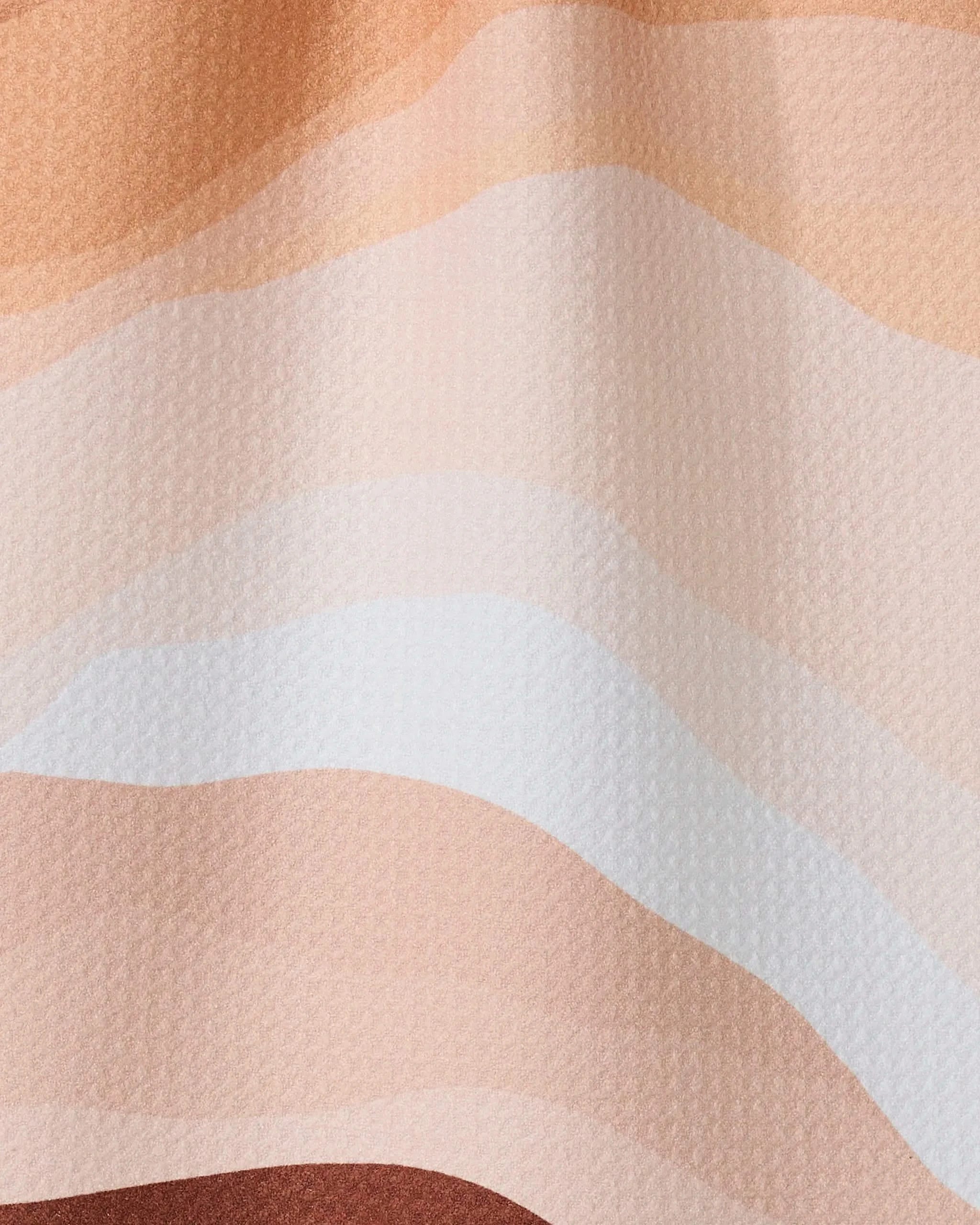 Levels of Fall by GEOMETRY features wavy, horizontal layers in beige, peach, tan, and brown tones—evoking a stylized landscape. This design is the inspiration for an ultra-absorbent towel made from recycled materials.