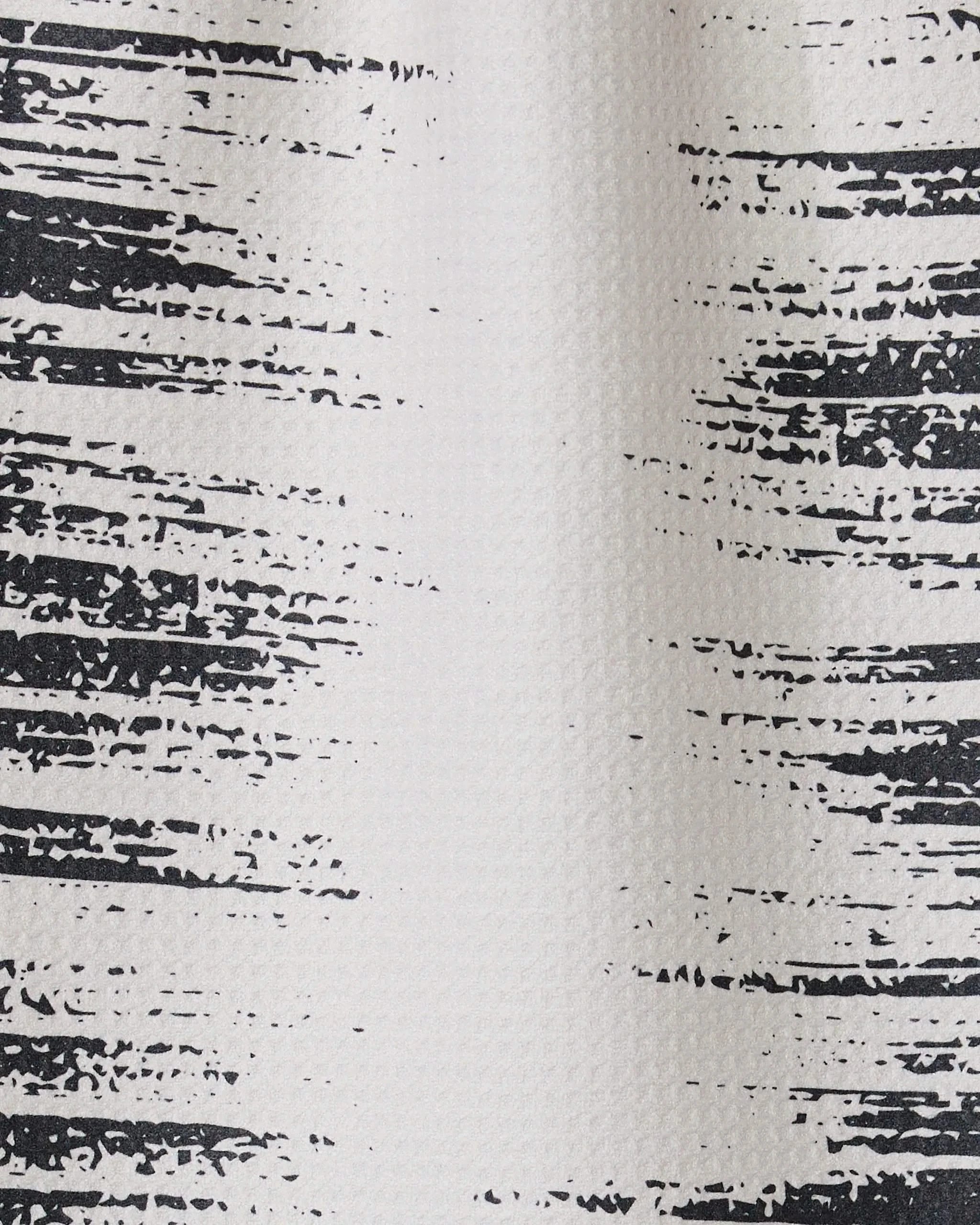 Close-up of the Worn Edges towel by GEOMETRY shows a textured white surface with irregular black lines, resembling a distressed or painted pattern typical of ultra-absorbent or recycled kitchen towels.