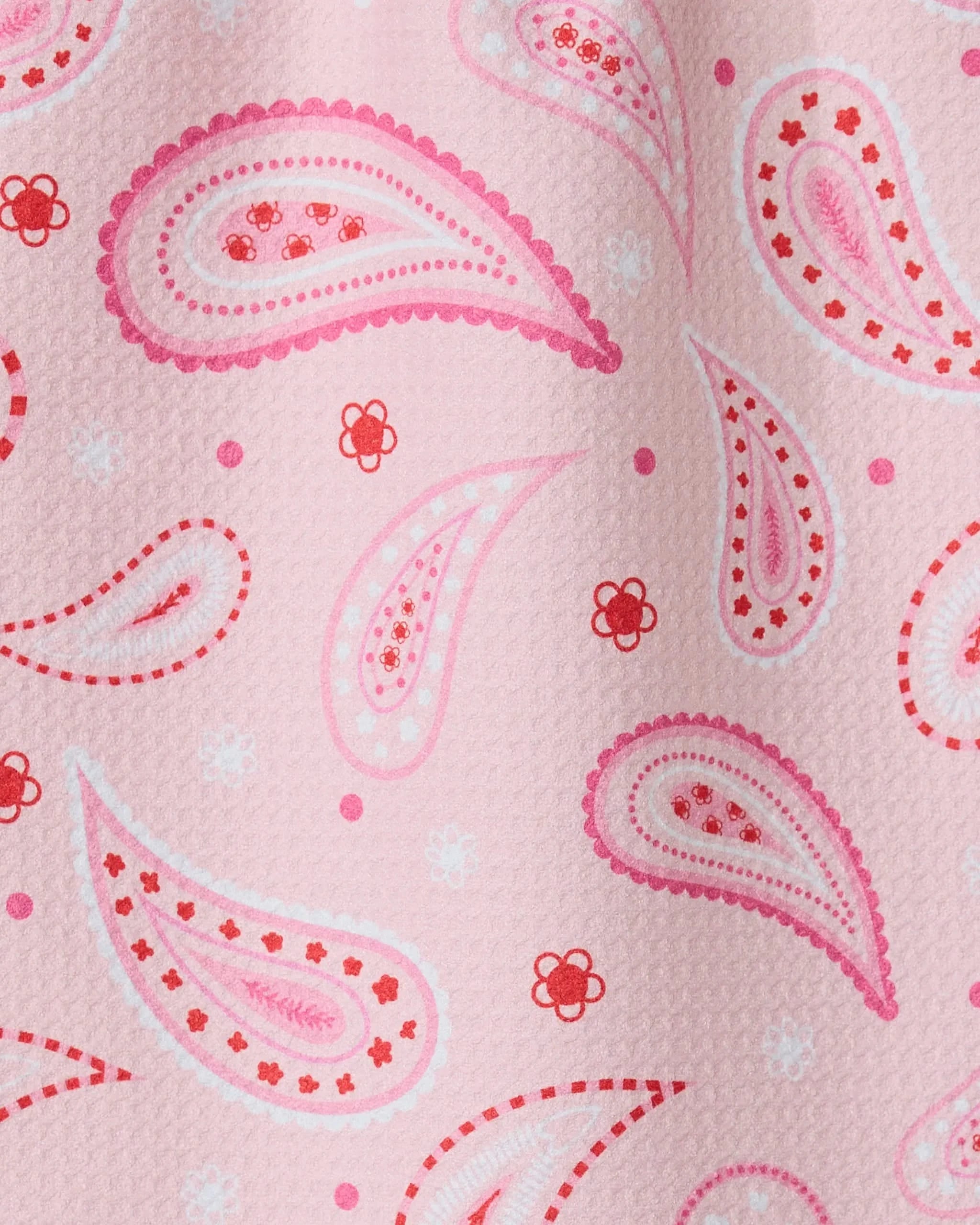 Close-up of the GEOMETRY Sweet Paisley ultra-absorbent towel with pink textured fabric, accented by paisley patterns and small floral designs in pink, red, and white.