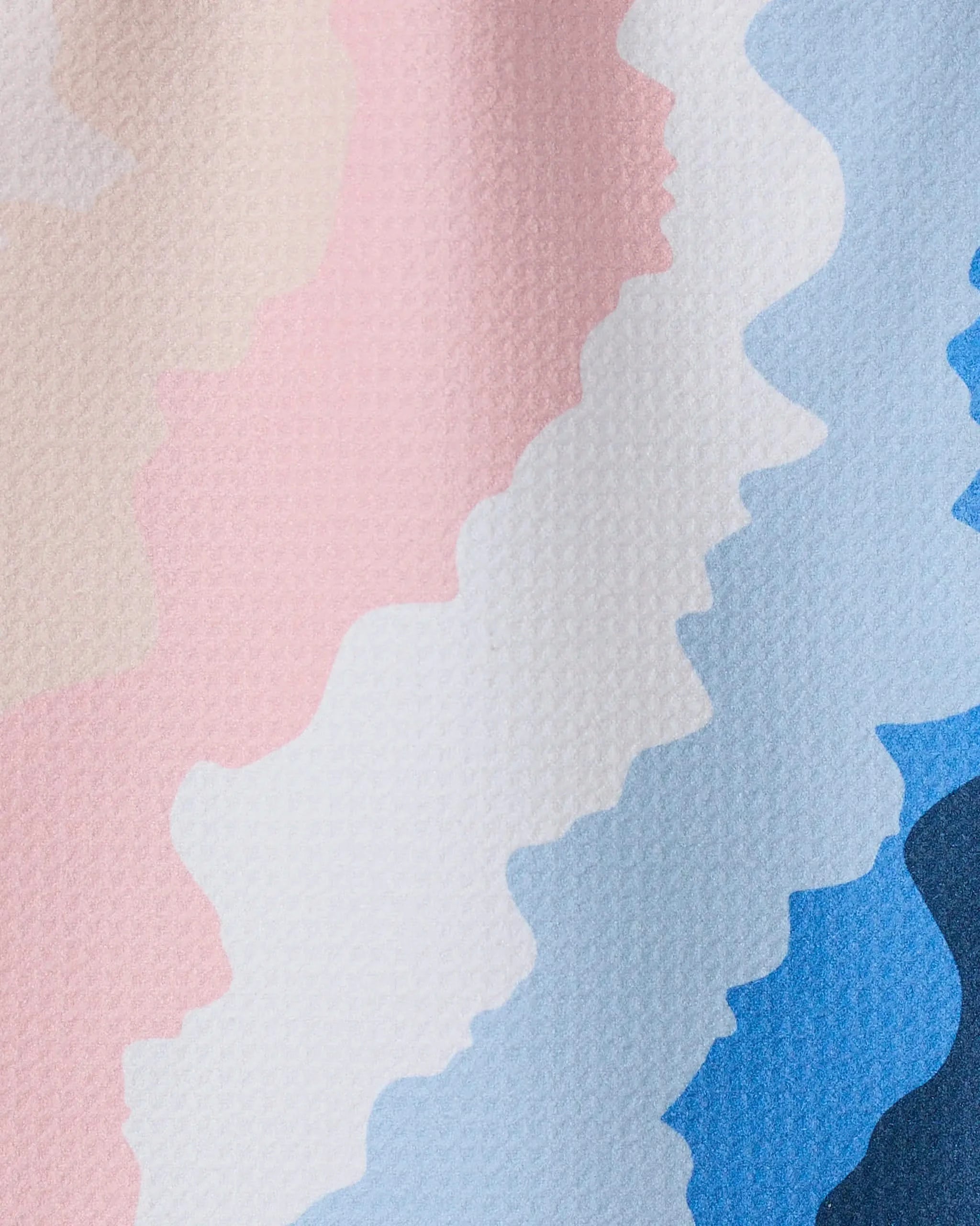 GEOMETRY’s “Shore” features wavy, horizontal stripes in pastel pink, cream, white, light blue, and blue on a lightly textured surface, with colors blending softly in a zigzag pattern reminiscent of recycled kitchen towels.