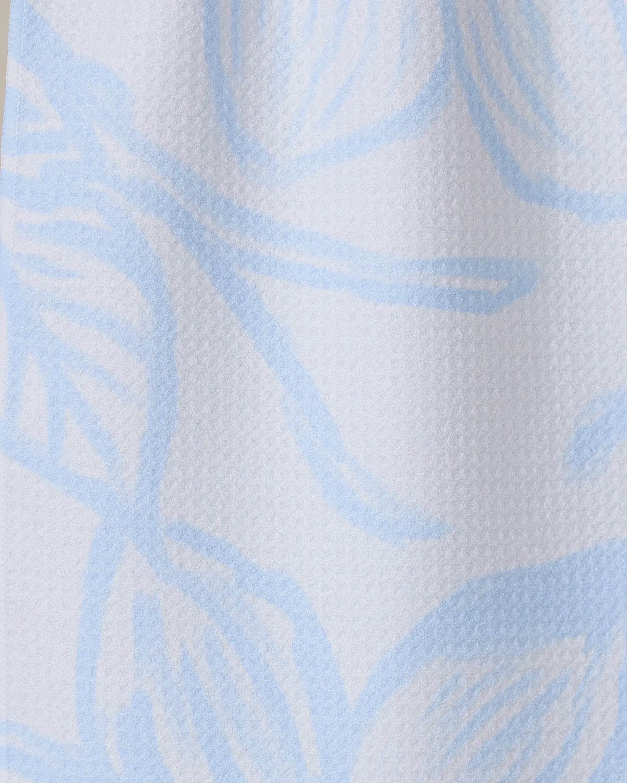 Close-up of GEOMETRY’s Something Blue, featuring textured white Geoweave fabric with a soft surface and a light blue abstract floral pattern of large, flowing lines and petal-like shapes.