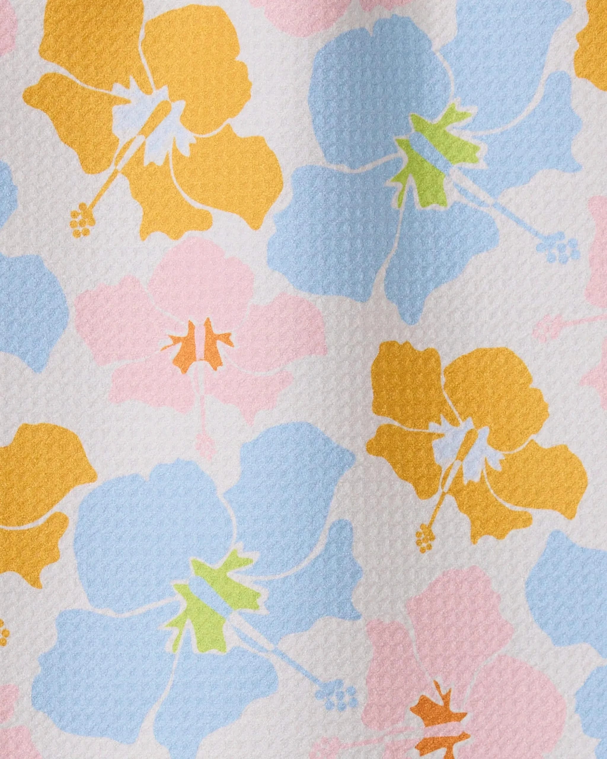 The GEOMETRY Hula Hues bar towel features a textured white background adorned with ultra-absorbent fabric and bold hibiscus flowers in yellow, blue, and pink with colorful centers.