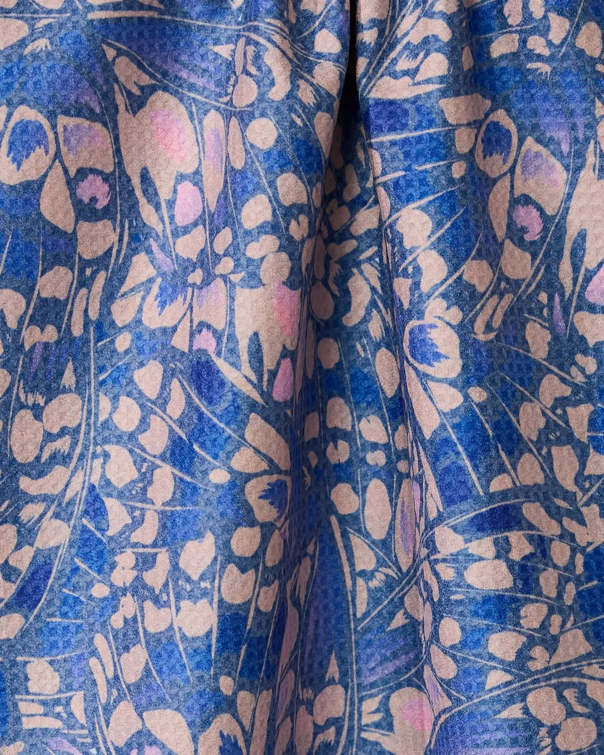 Close-up of Geometrys Lav tea towel, double-sided with a blue and light pink abstract butterfly or petal pattern, featuring intricate overlapping shapes and a soft, flowing texture.