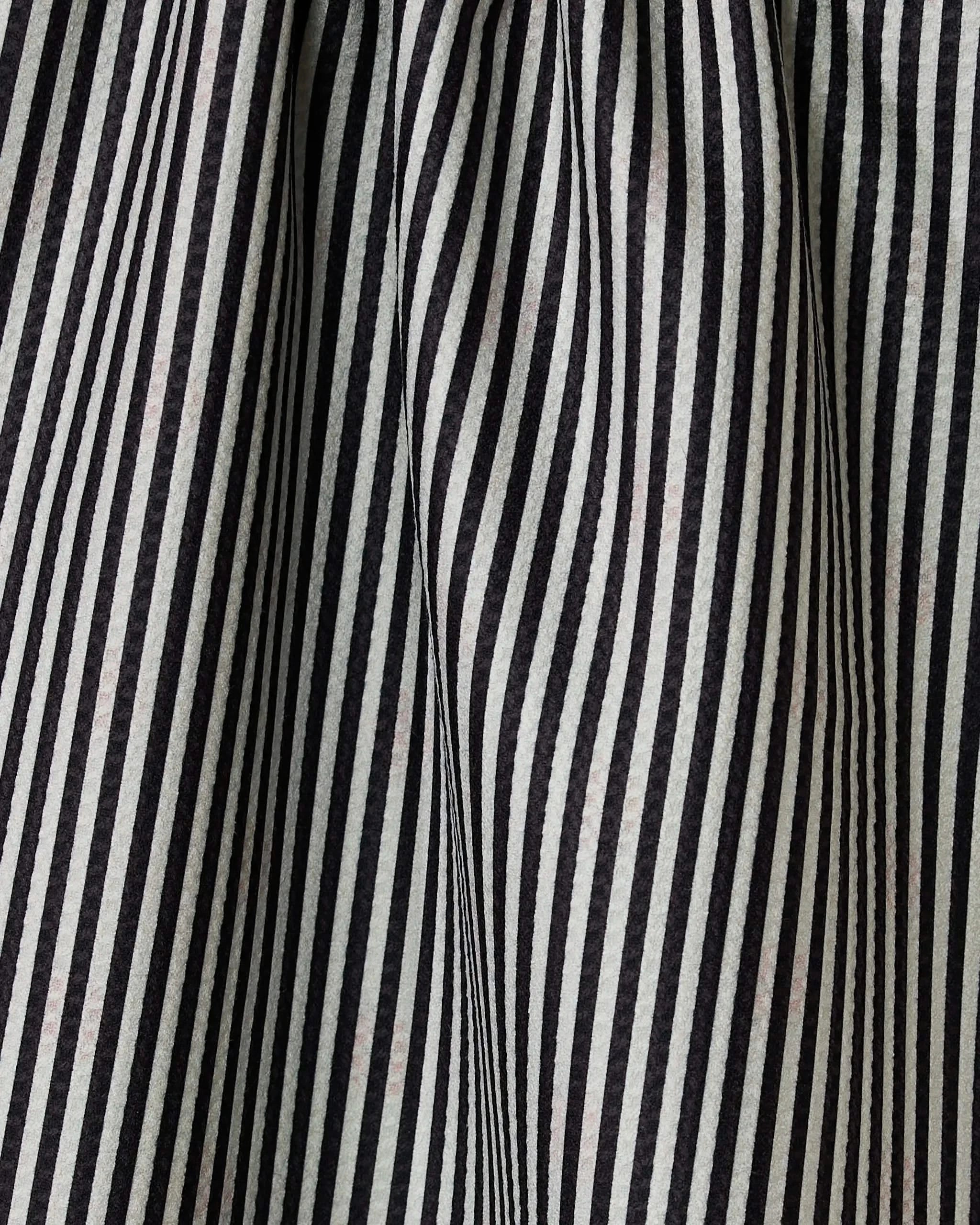 Close-up of black and white vertical stripes on the double-sided Lady tea towel by Geometry, showing folds and creases that create a wavy, textured pattern.