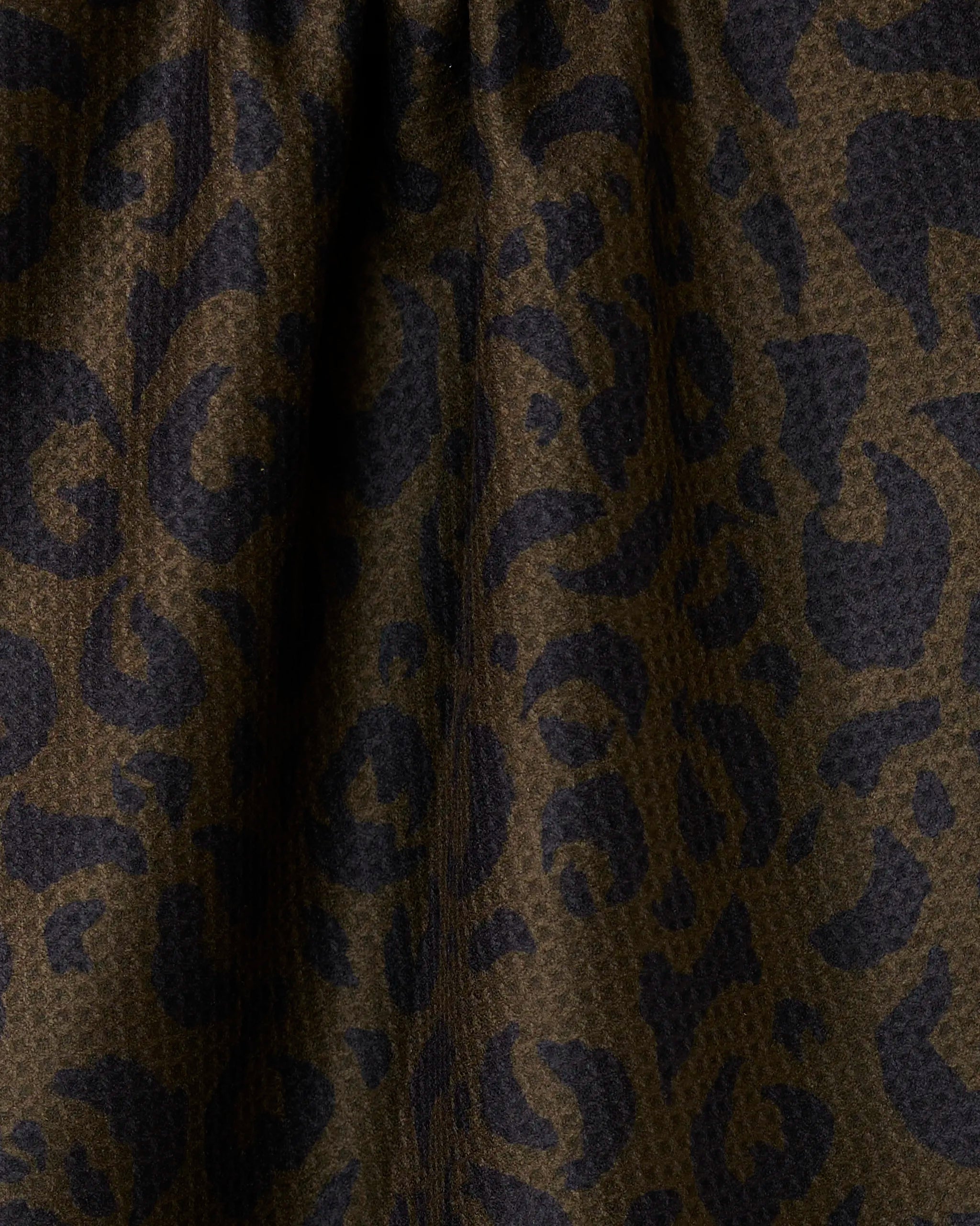 A close-up of Geometry’s Safari tea towel in dark brown with a black leopard print, highlighting its stylish folds and quick-dry, super absorbent fabric.