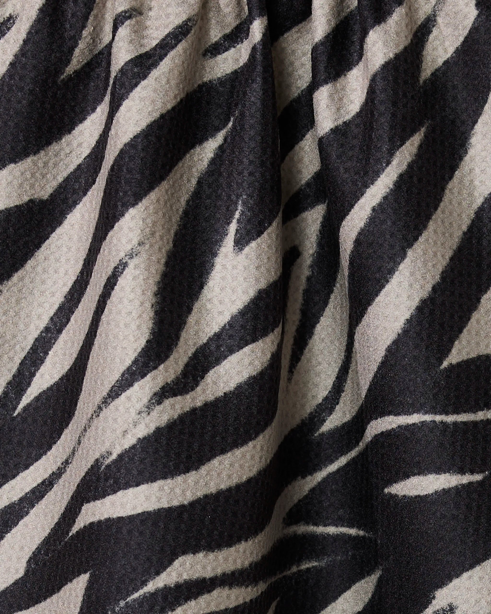 Close-up of the Safari tea towel by Geometry, featuring a black and white zebra stripe pattern with visible texture and folds in its absorbent, quick-dry fabric.