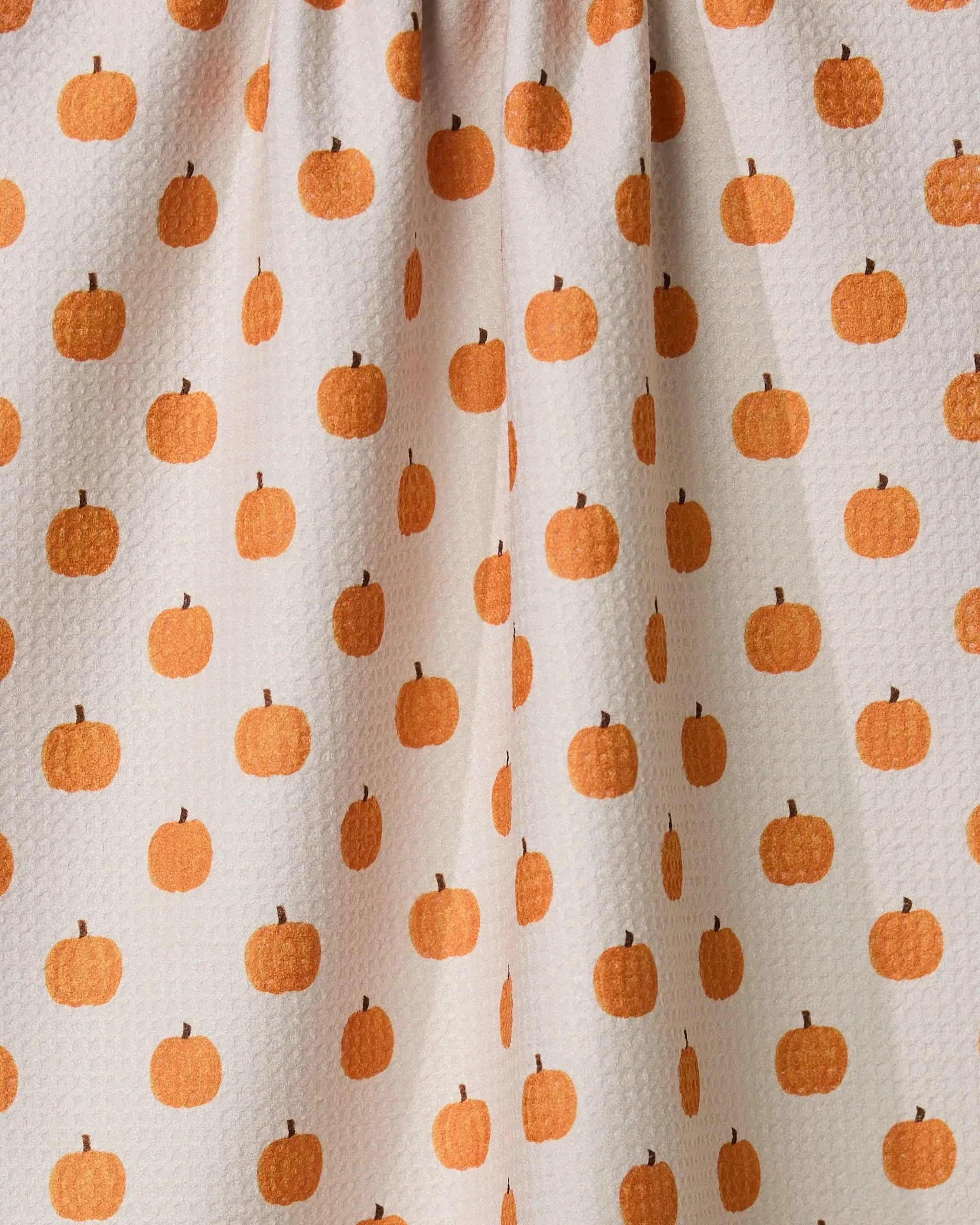 The Geometry Patchwork kitchen towel features a white textured design with small orange pumpkins in neat rows. Slight gathering at the top adds style and function, making this eco-friendly tea towel a charming home essential.