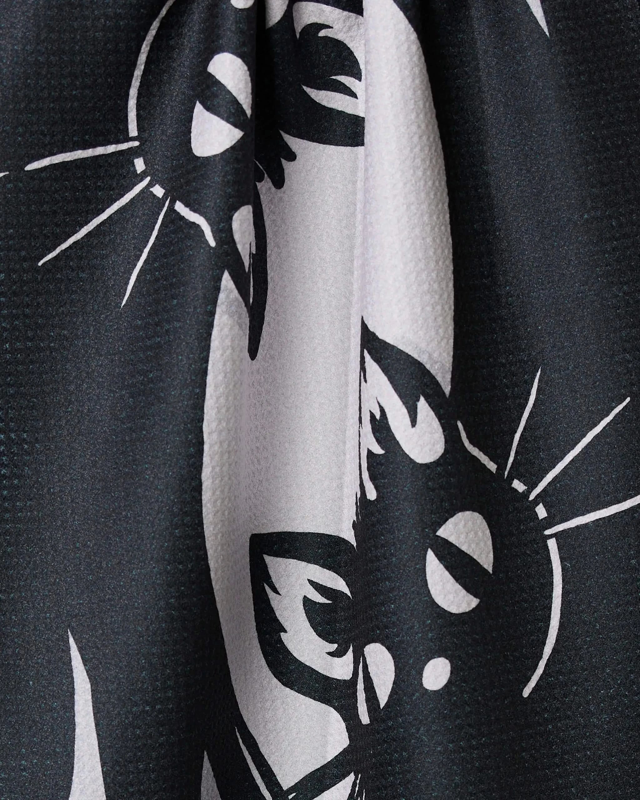 Geometry’s Night Zoomies tea towel features a bold, black-and-white abstract cat face print with wide eyes and whiskers. Made from recycled materials, it’s textured, ultra-absorbent, and slightly draped.
