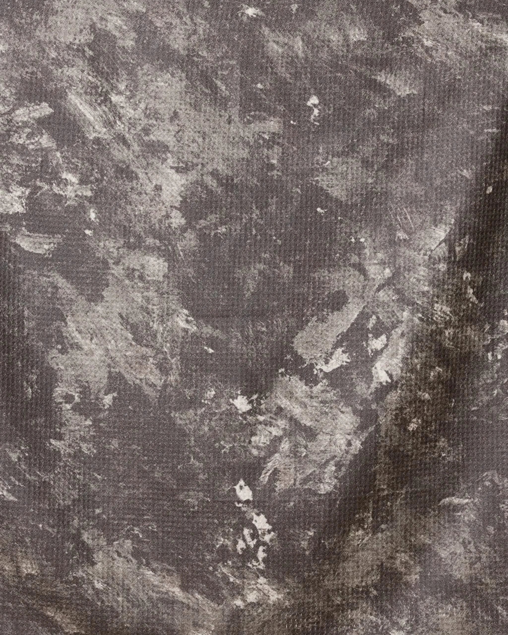 A close-up of Spooky Ghost Walk Orange by Geometry shows a textured surface with irregular gray and white patches resembling worn stone or concrete, made from recycled materials, featuring rough brush-like patterns.