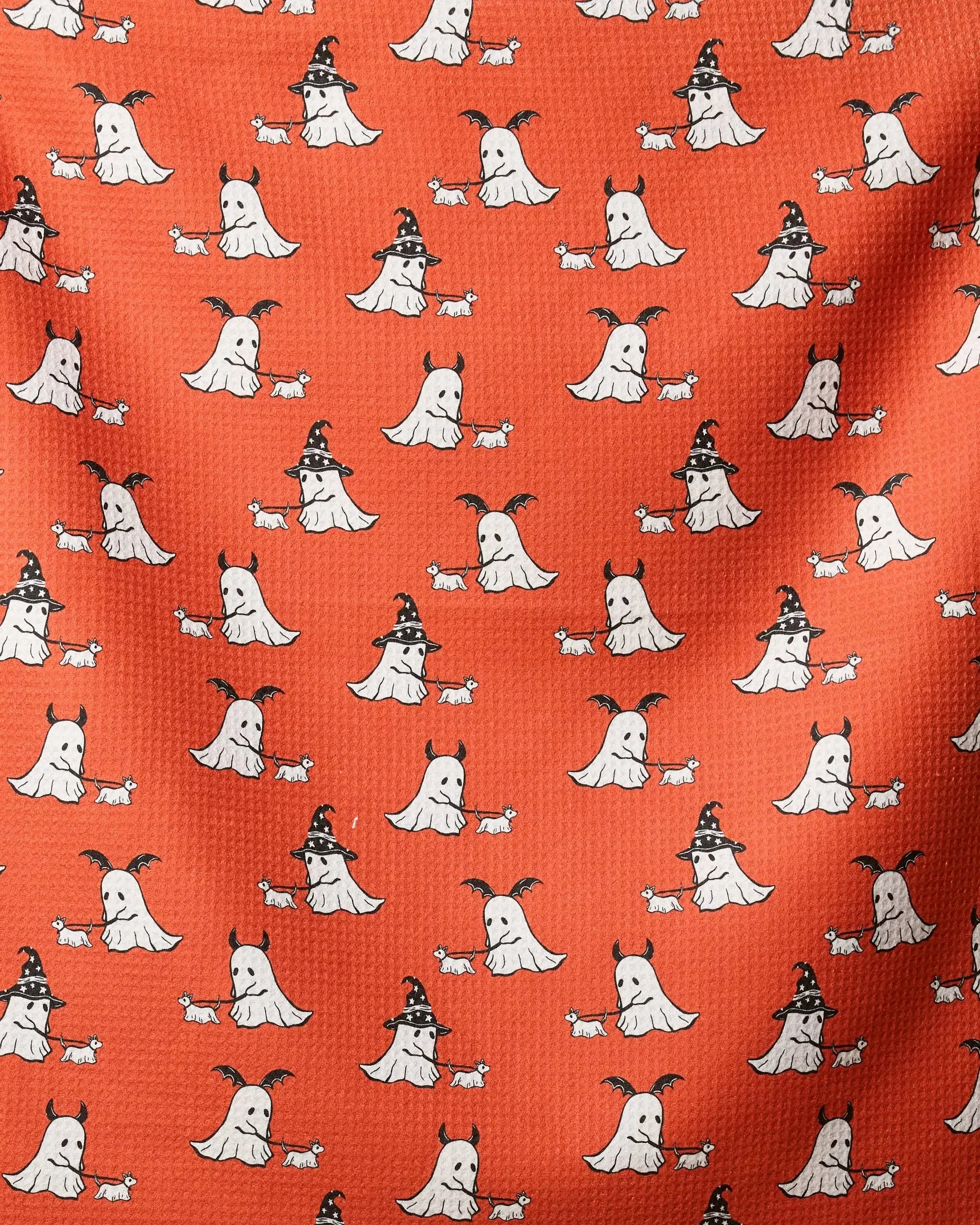 The Spooky Ghost Walk Orange dog towel by Geometry features a pattern of cute white ghosts with black witch hats and small white dogs on an orange background, evenly repeating on a highly absorbent, recycled material.