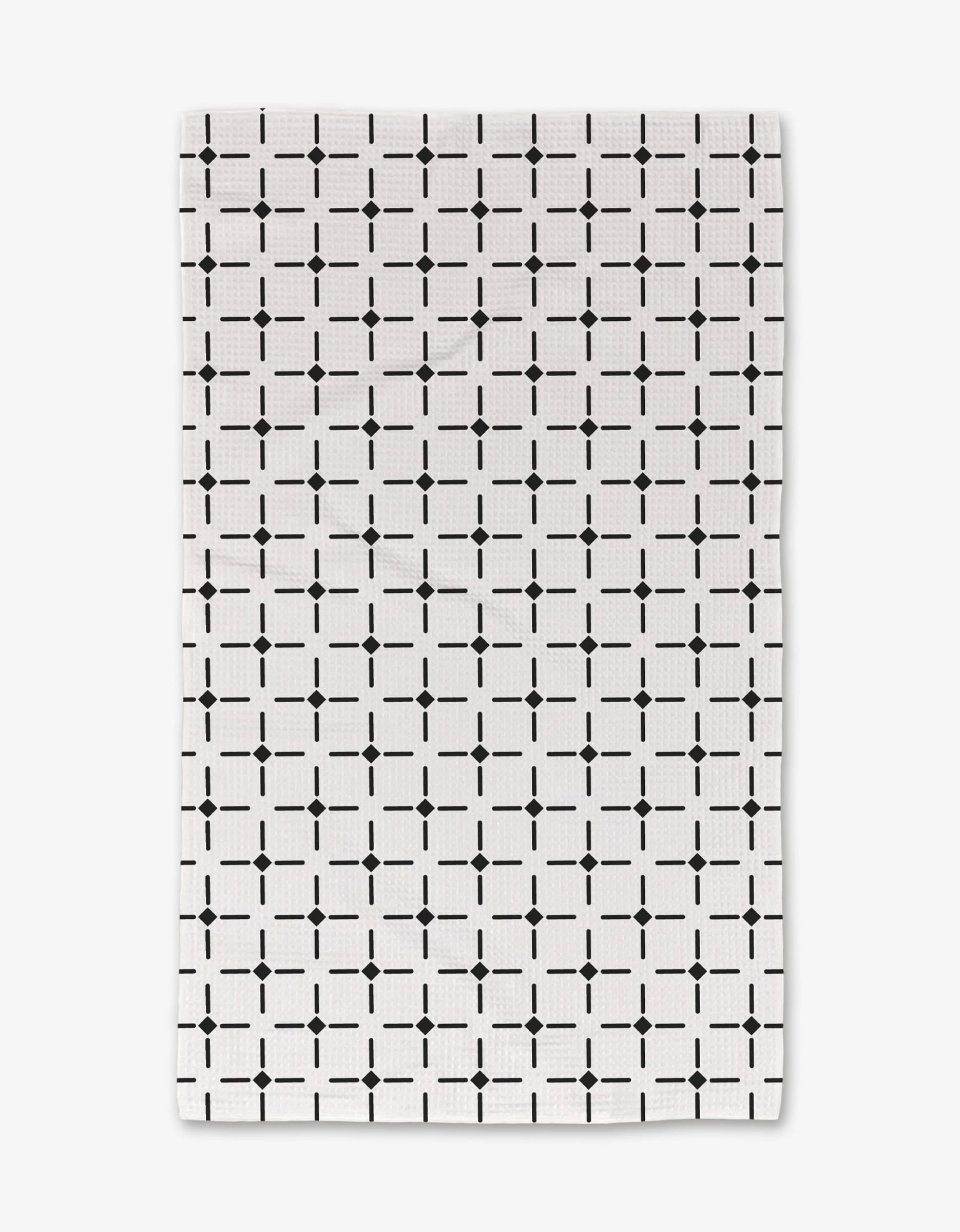 The Collins hand towel by Charlie Rowan Designs features a white background with a black geometric grid pattern and is crafted from ultra-absorbent material, offering both style and functionality.
