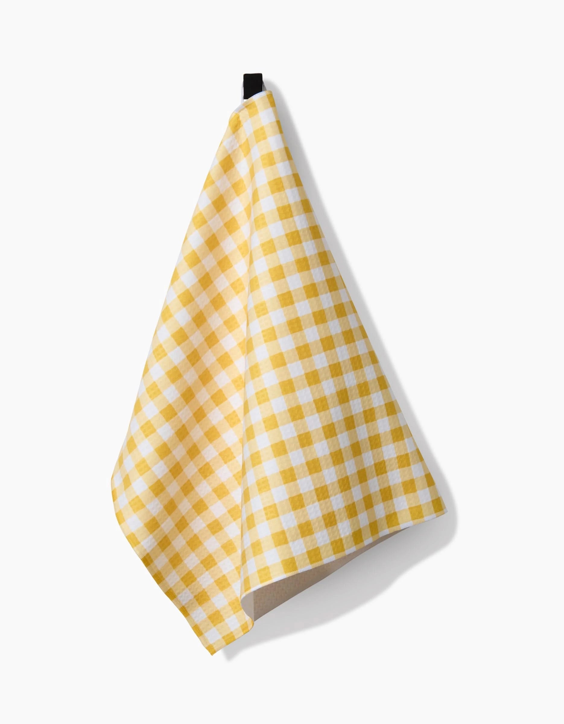 The Danelys Sidron Golden Plaid dish towel, featuring a yellow and white checkered design, hangs by a black loop against a plain white background.