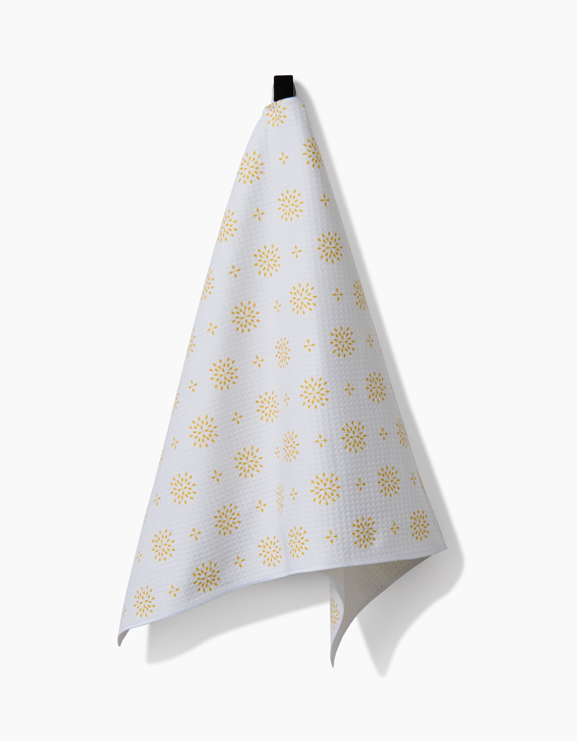 The Morning Petals by Danelys Sidron is a white cloth featuring a yellow starburst pattern, crafted with Geoweave technology, hanging from a black loop against a plain white background.