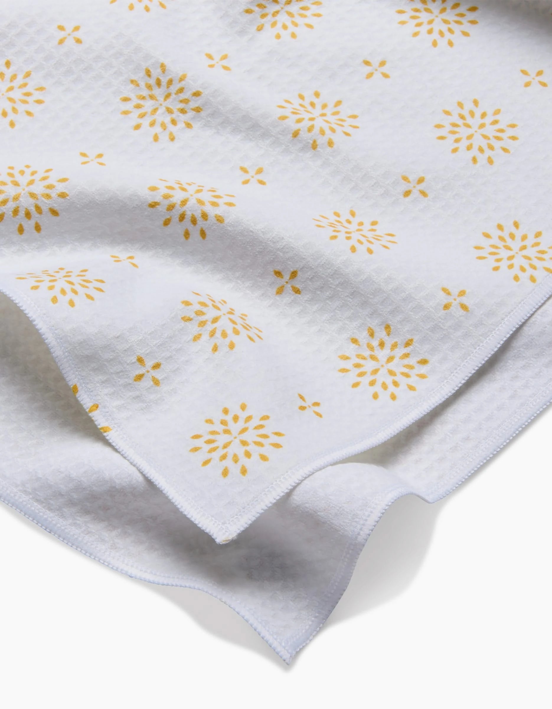 Morning Petals by Danelys Sidron features white textured fabric with a subtle grid pattern and yellow floral prints. Ultra-absorbent, lightweight, and flexible—perfect for Luxe Hand Towels.