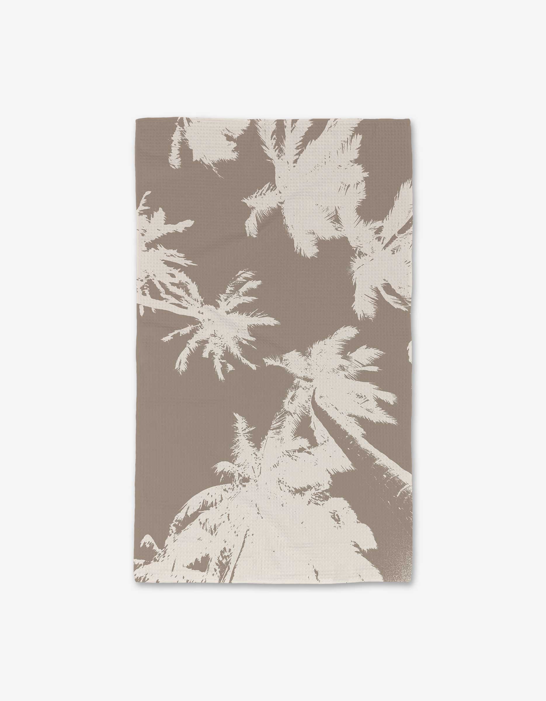 The GEOMETRY Sandy Palms towel showcases beige and light brown palm tree silhouettes on a plain background, crafted with Geoweave technology for extra softness and durability.