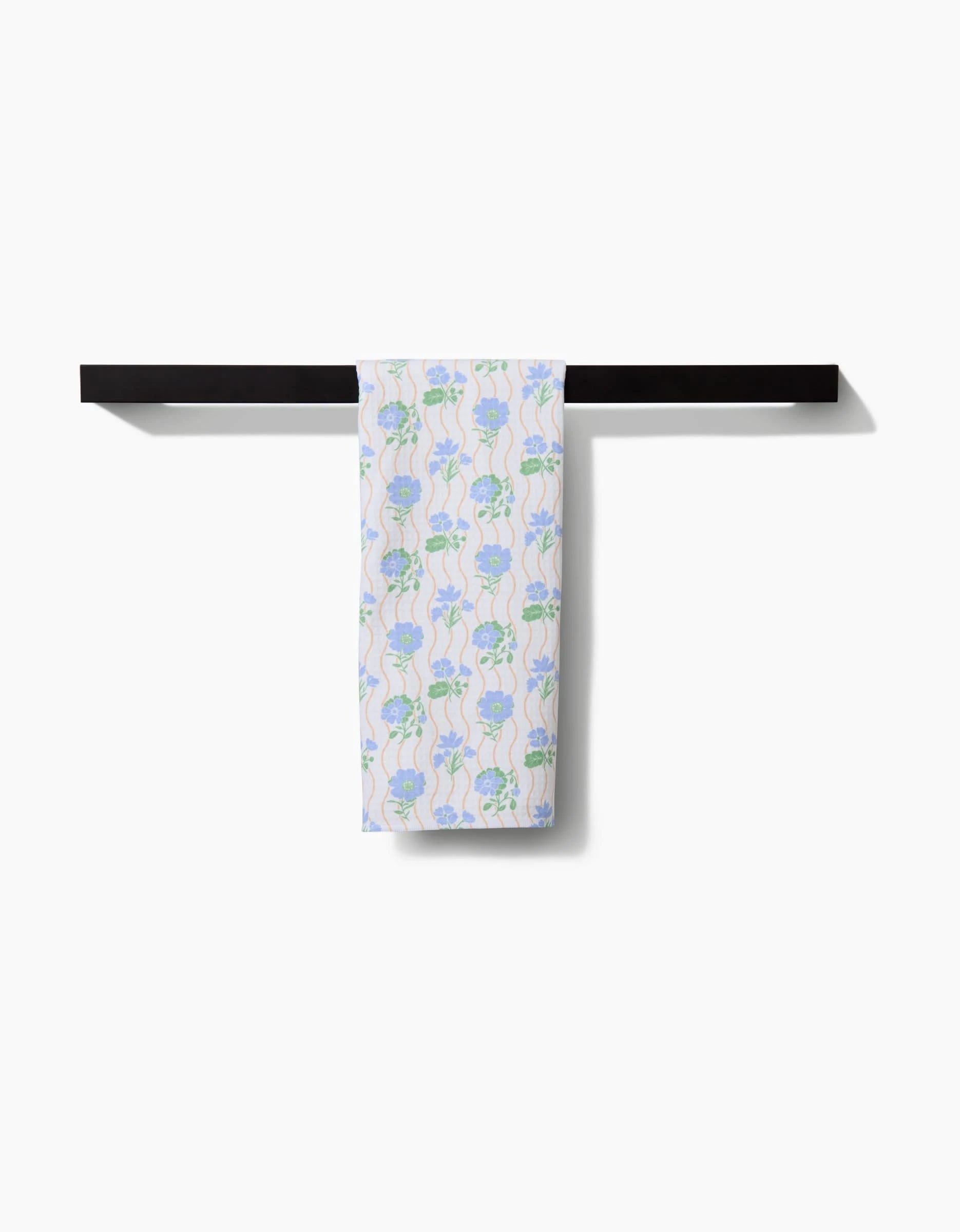 The Danelys Sidron Spring Wave towel, featuring a blue and green floral pattern and made with ultra-absorbent Geoweave technology, hangs neatly on a simple black towel bar against a white background.
