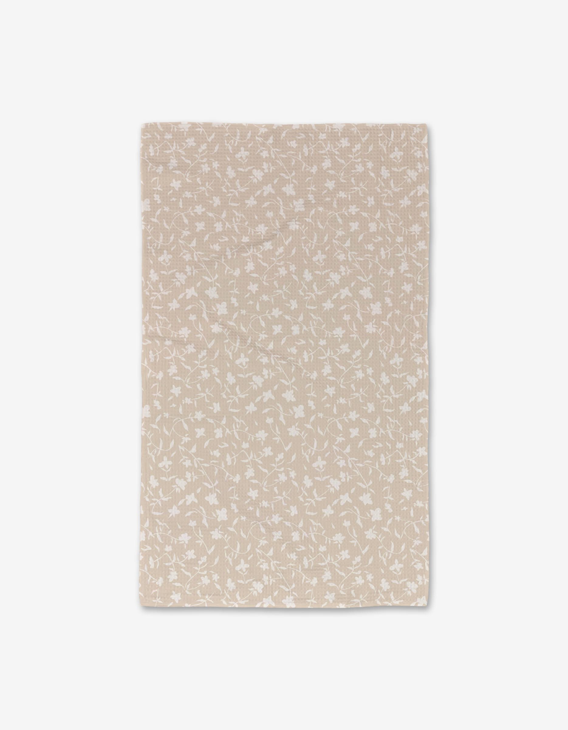 The Tiny Floral by Aubrey Fairchild is a beige, rectangular ultra-absorbent cloth featuring a subtle white floral pattern, photographed on a plain white background.