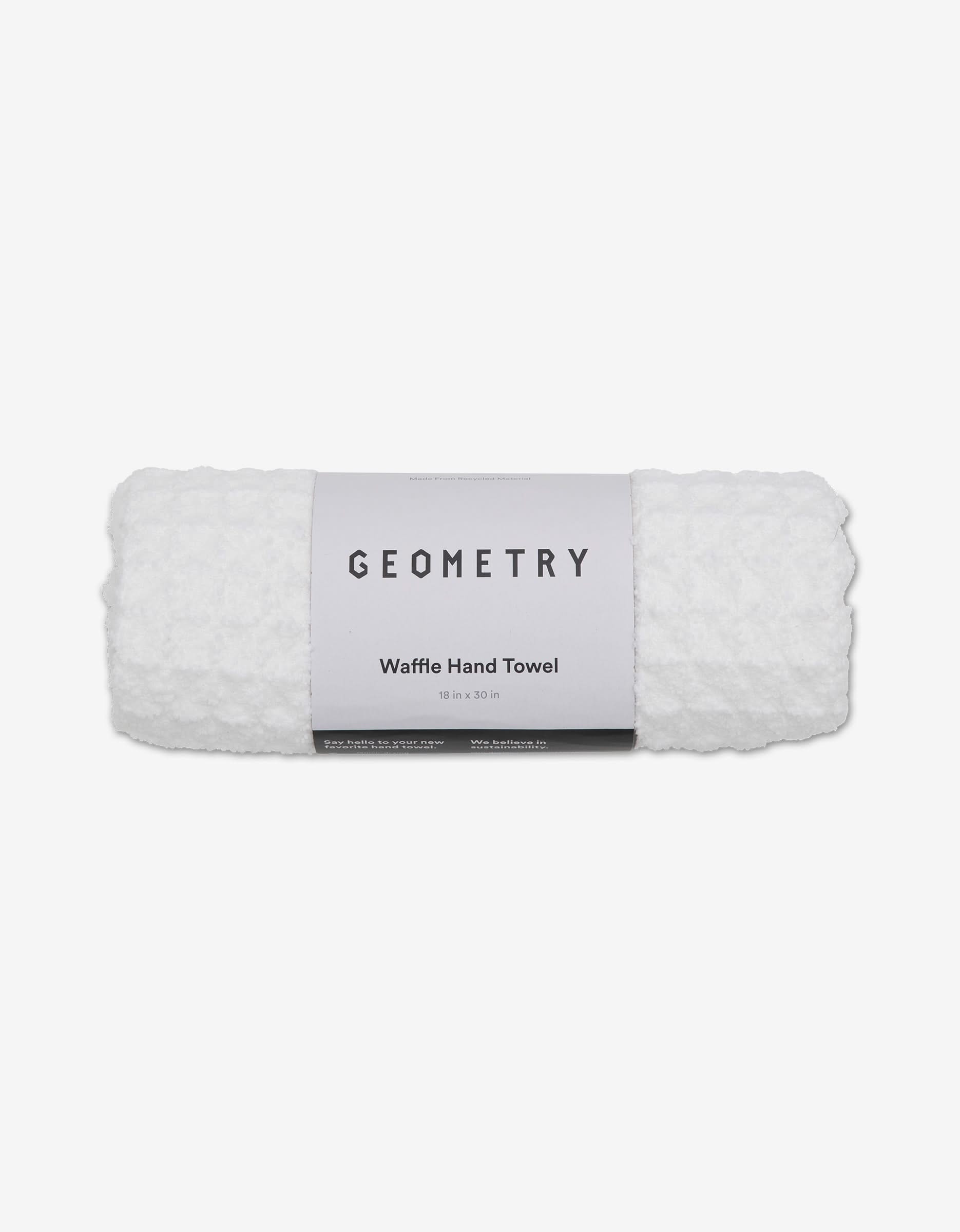 A rolled GEOMETRY Cloud white waffle-textured hand towel made from recycled materials, showing the GEOMETRY label, displayed on a plain white background.