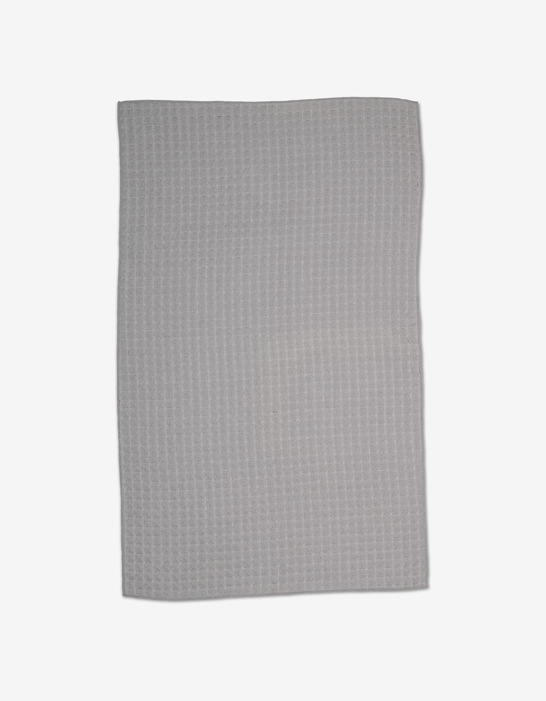 The GEOMETRY Stone hand towel, rectangular and light gray, is laid flat on a white surface to display its luxury waffle texture and ultra-absorbent design.