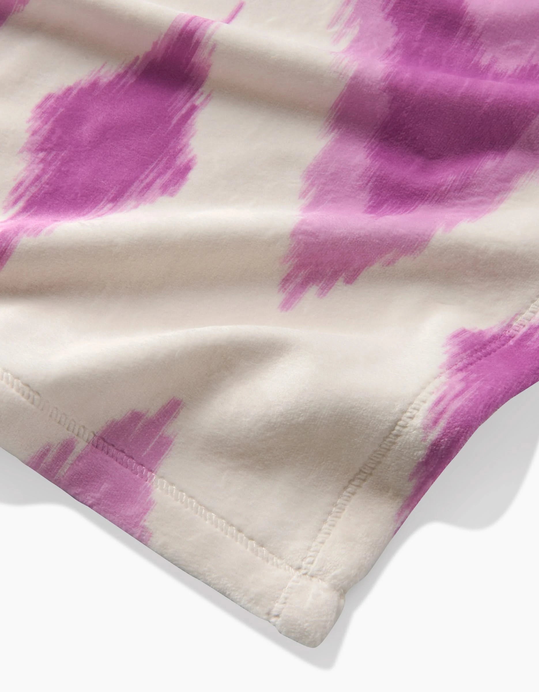 Close-up of Tulip Scatter fabric by Geometry, featuring purple brushstroke-patterned prints on beige, detailed hem stitching, and soft folds, crafted from recycled materials.