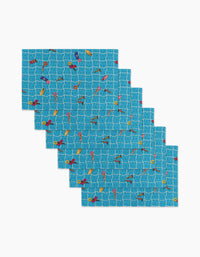 Six At The Pool rectangular blue reusable placemats by Geometry, each with a swimmers, ducks, and flamingos pool pattern over white tile-like grid lines—an eco-friendly alternative to Not Paper Towels.
