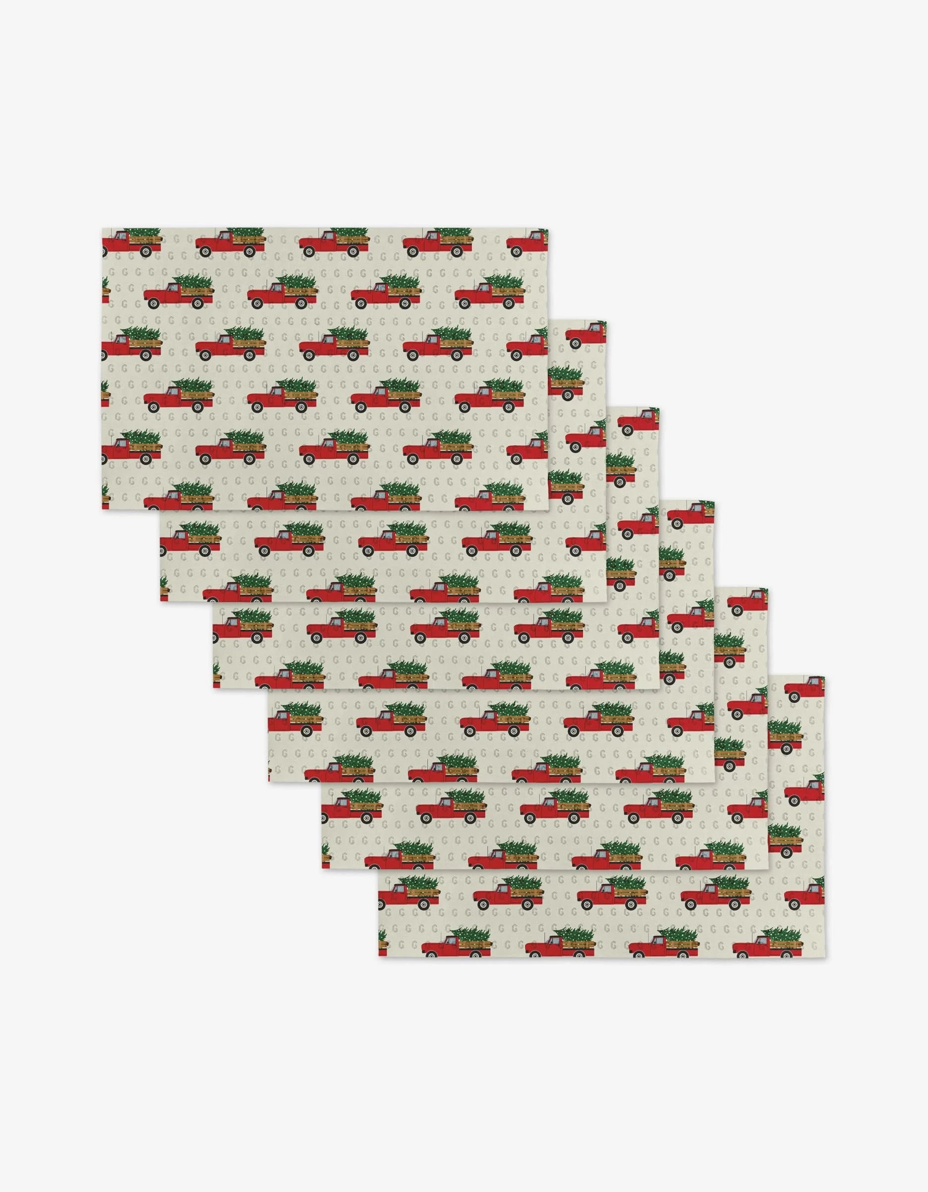 Christmas Ride by Megan Kampa: Set of 6 reusable rectangular placemats with red vintage trucks carrying Christmas trees on a white background with grey snowflakes—a stylish, eco-friendly alternative to disposable decor.