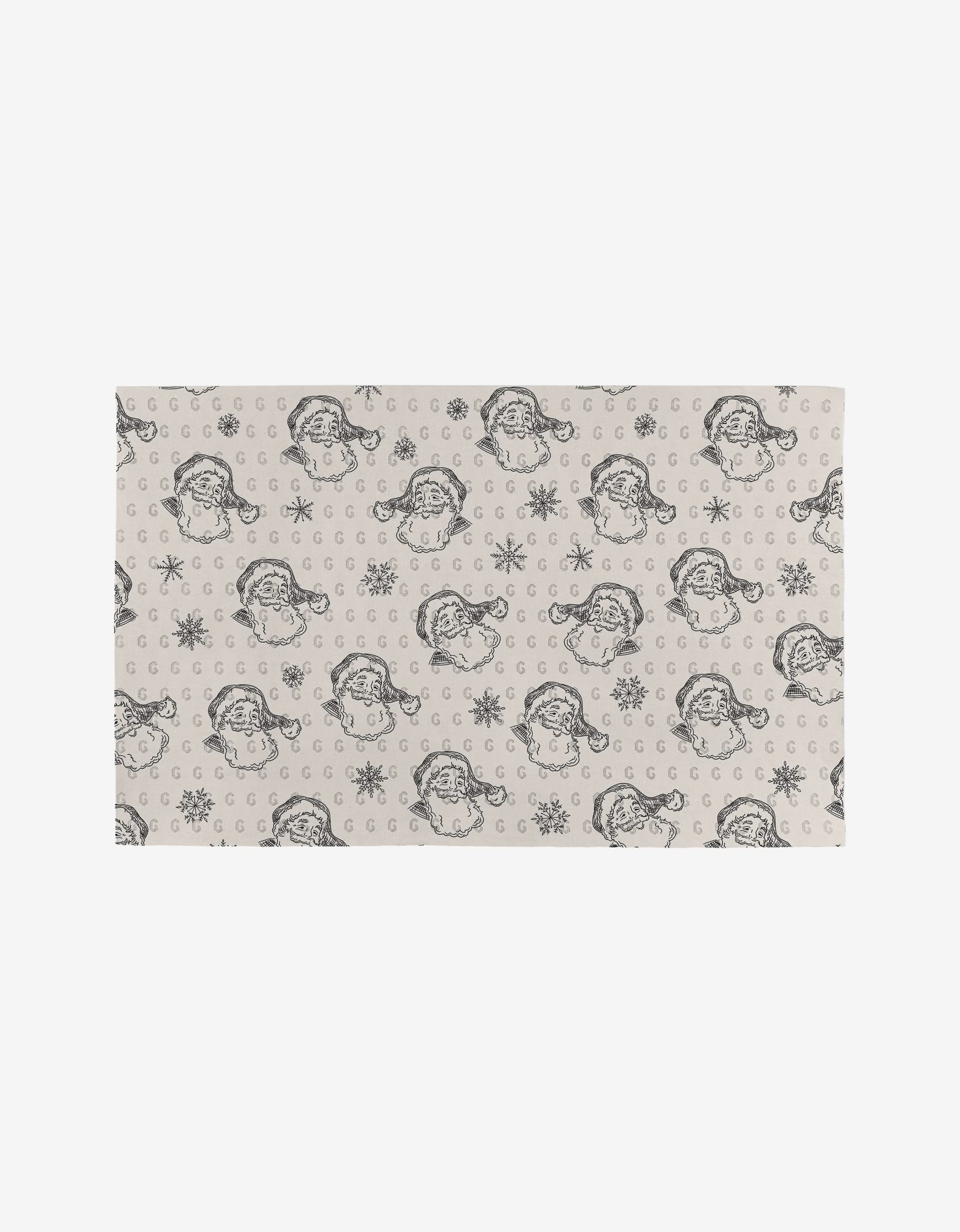 The Christmas Santa mat by Aubrey Fairchild is a beige rectangular rug made from post-consumer recycled materials, featuring black vintage-style Santa faces, snowflakes, and crescent moons in a repeating pattern.