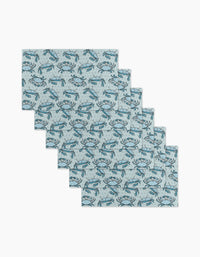 Six Mindfulnice Coastal Crew reusable paper towels with a light blue background and repeating blue crab pattern are arranged in a staggered stack on a white surface.