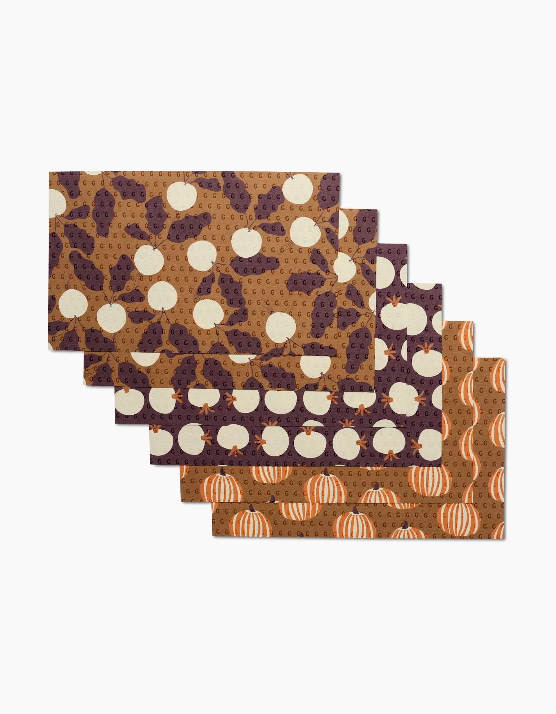 Set your fall table with Lizzie Clark’s Dancing Fall—six rectangular placemats featuring autumn pumpkin designs in brown, orange, and purple. Arrange them in a staggered stack and pair with eco-friendly paper towels for festive style.