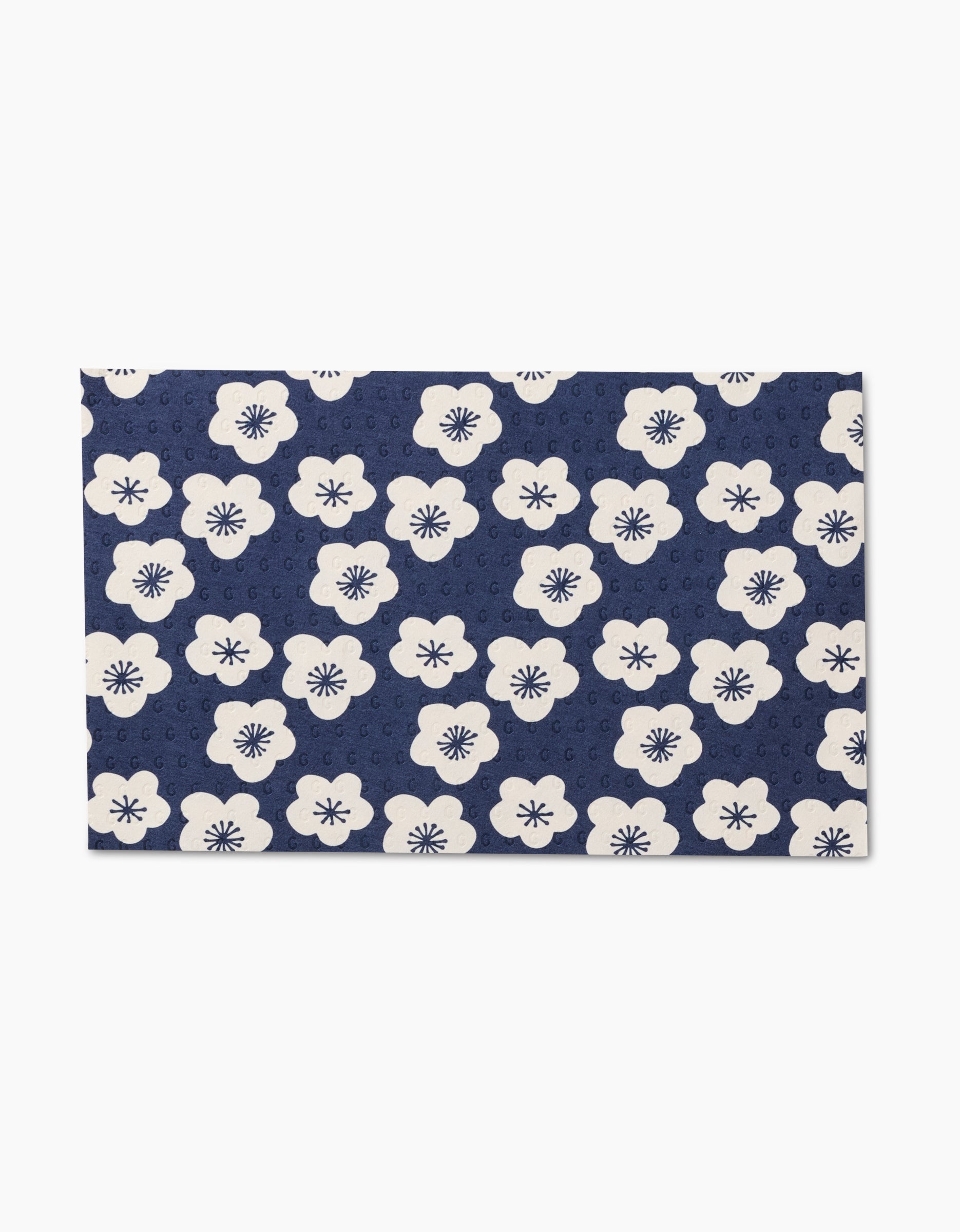 The Every Sunday mat by GEOMETRY features a dark blue background with a repeating pattern of white flowers and navy centers—an eco-friendly, reusable alternative to disposable options for your home.