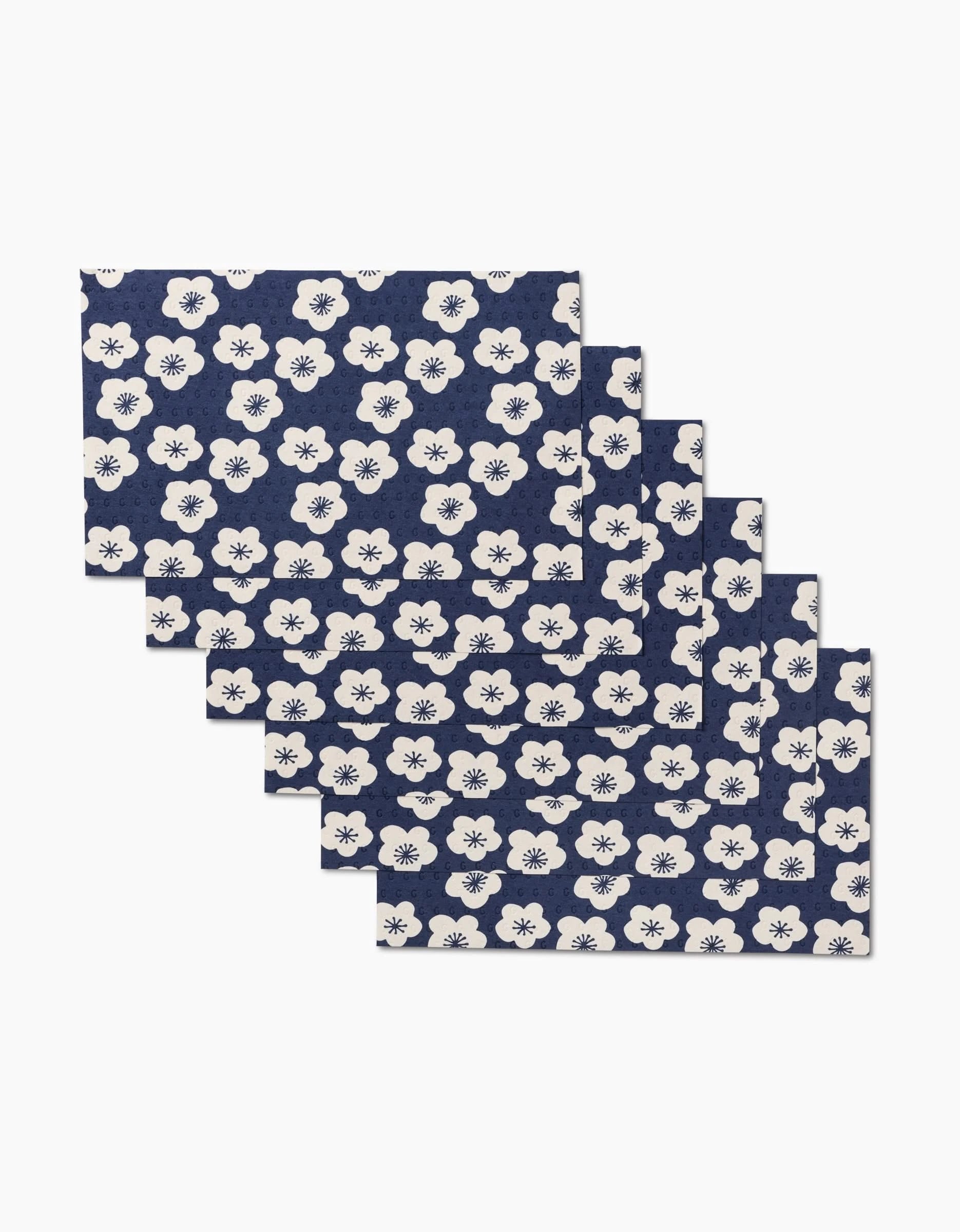 Six Every Sunday placemats by GEOMETRY in navy blue with a white floral pattern, fanned out for display—an eco-friendly, reusable alternative to disposable tableware.