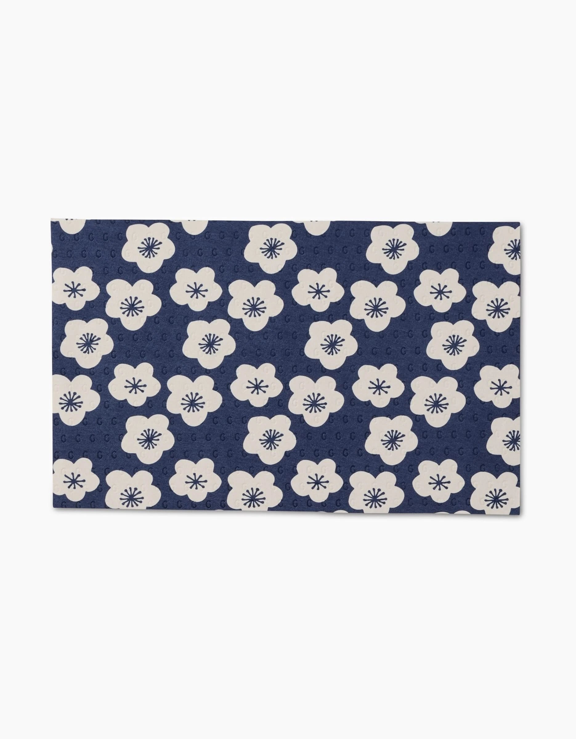 Every Wish by GEOMETRY is a rectangular, reusable mat featuring white flowers with dark centers on a navy blue background, along with subtle circular motifs—an eco-friendly alternative to Not Paper Towels.