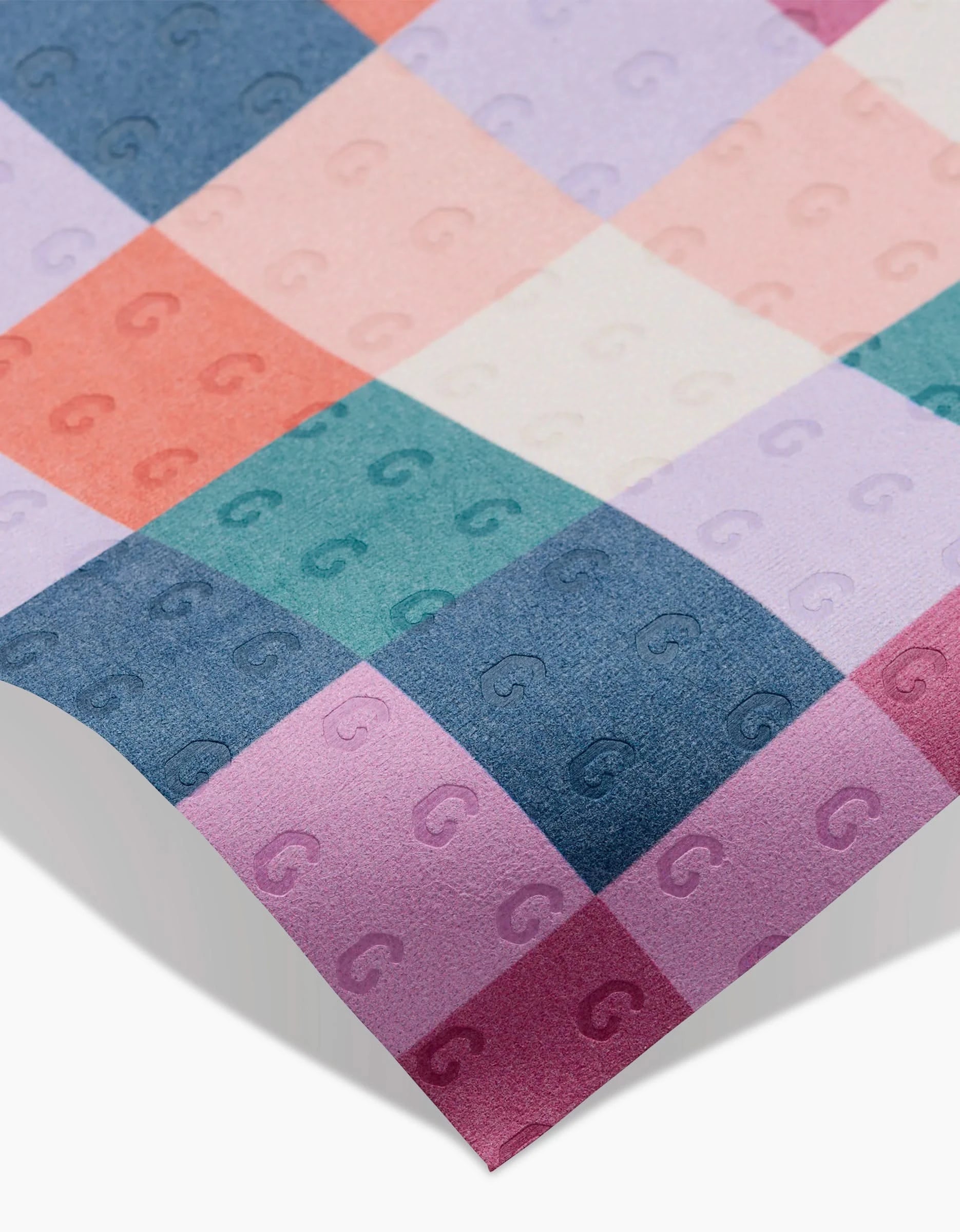A close-up of Claire Iglesias’ Fall Checkers reusable fabric, showcasing its multicolored checkered pattern with embossed G motifs in pink, purple, blue, green, and red. The eco-conscious material’s unique texture is highlighted at an angle.