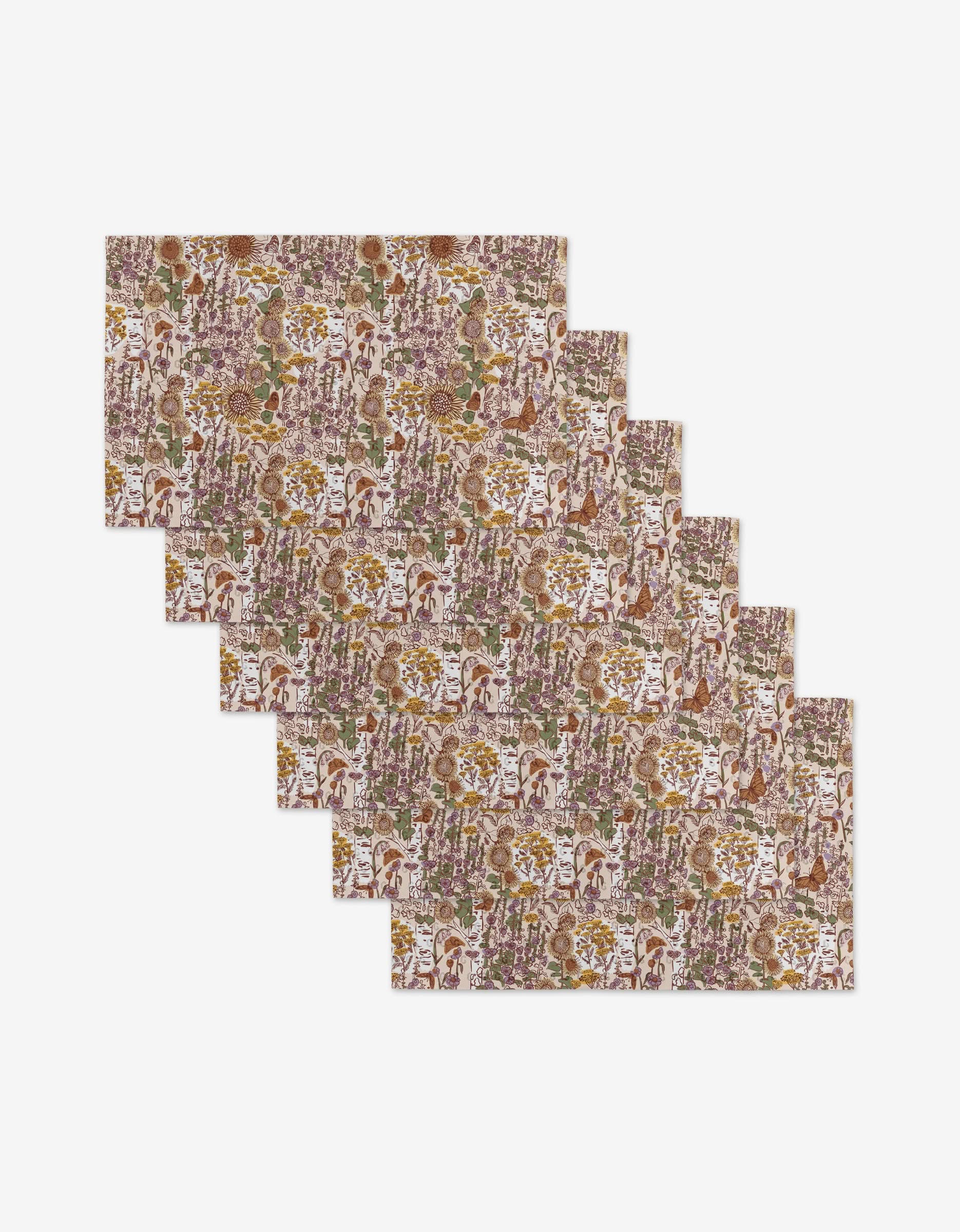 Six “Fall Forest” placemats by Elisabeth Wing, featuring a colorful floral and leaf pattern in brown, green, purple, and yellow, are arranged overlapping on white—an eco-friendly choice for your table.