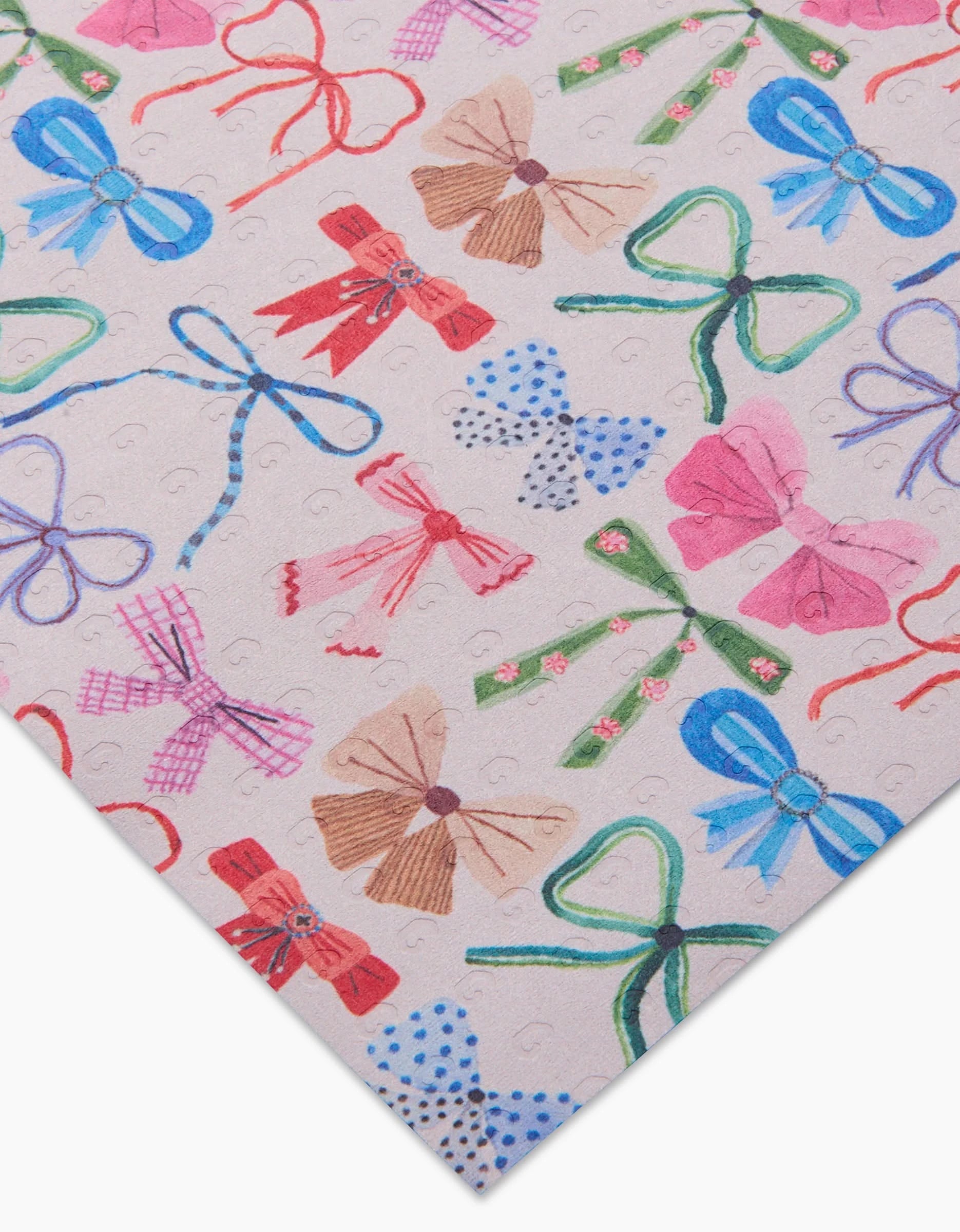 A close-up of the Family Christmas reusable paper towels by Daria Solak, featuring colorful, hand-drawn bows in various styles on a light background. The eco-friendly towels are pictured at an angle with one corner pointed.