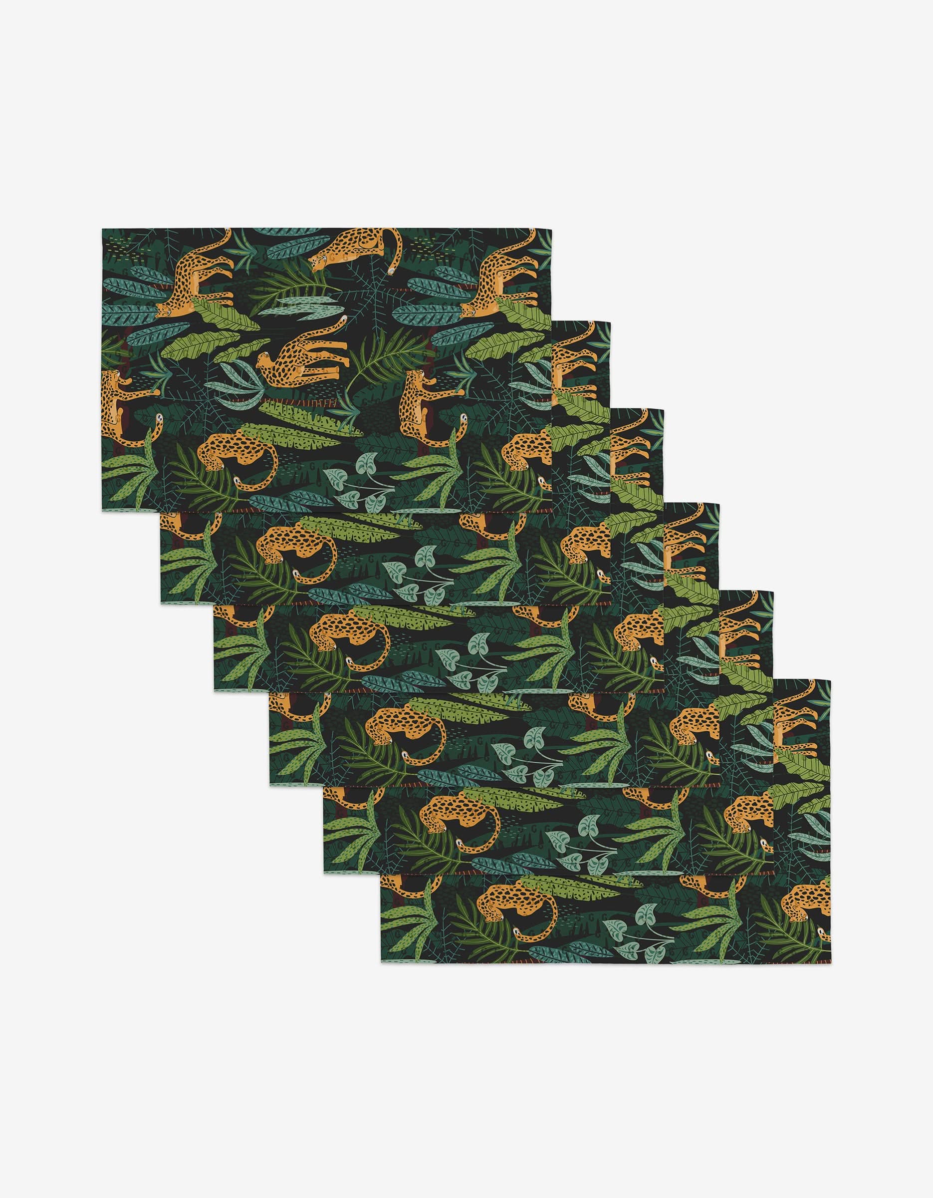 Six reusable rectangular placemats by GEOMETRY, called Feeling Spotty, feature green leaves, leopards, and lizards on a black background—an eco-friendly way to style your table. Shown fanned out.