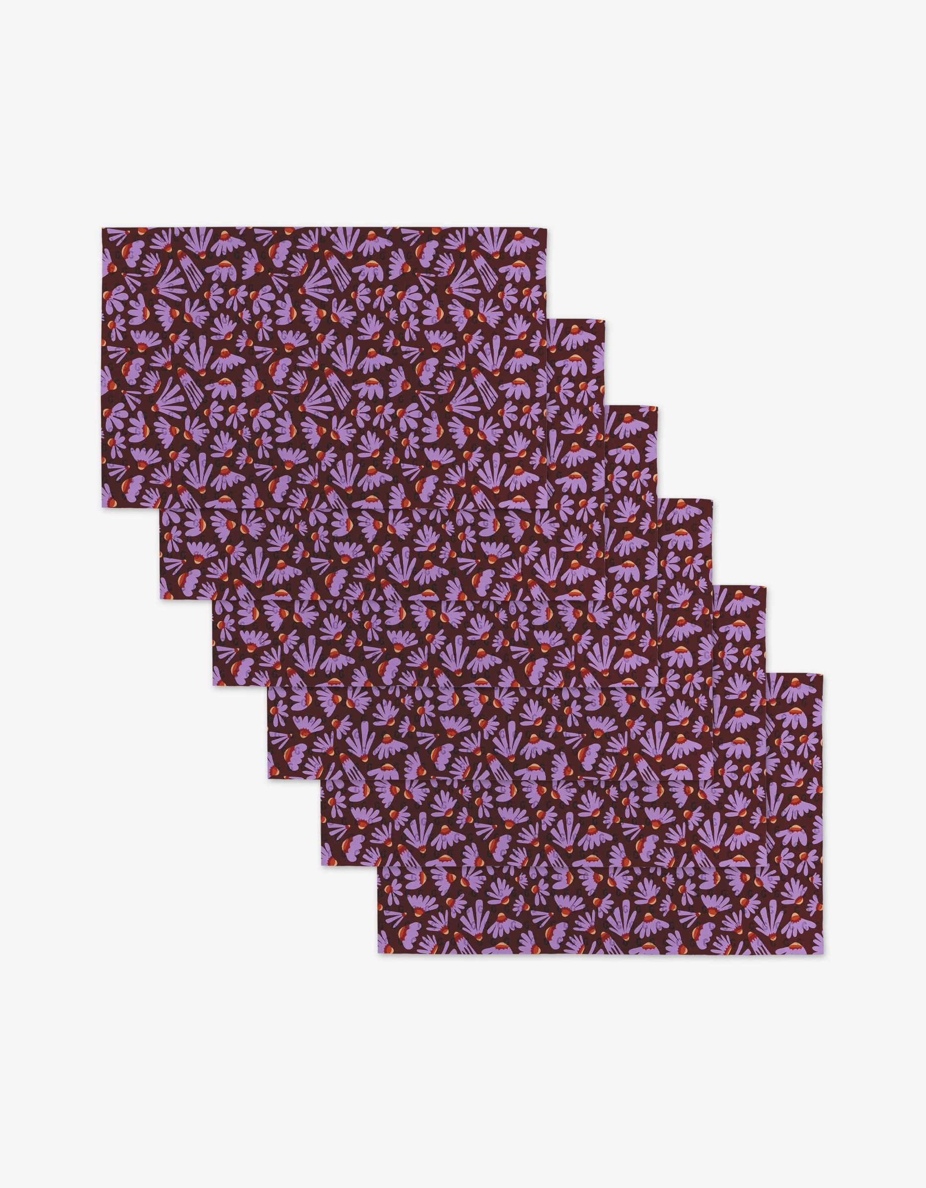 Five Flower Pop placemats by Elisabeth Wing, featuring a dark maroon background with lavender and pink floral patterns—an eco-friendly addition to your table setting.