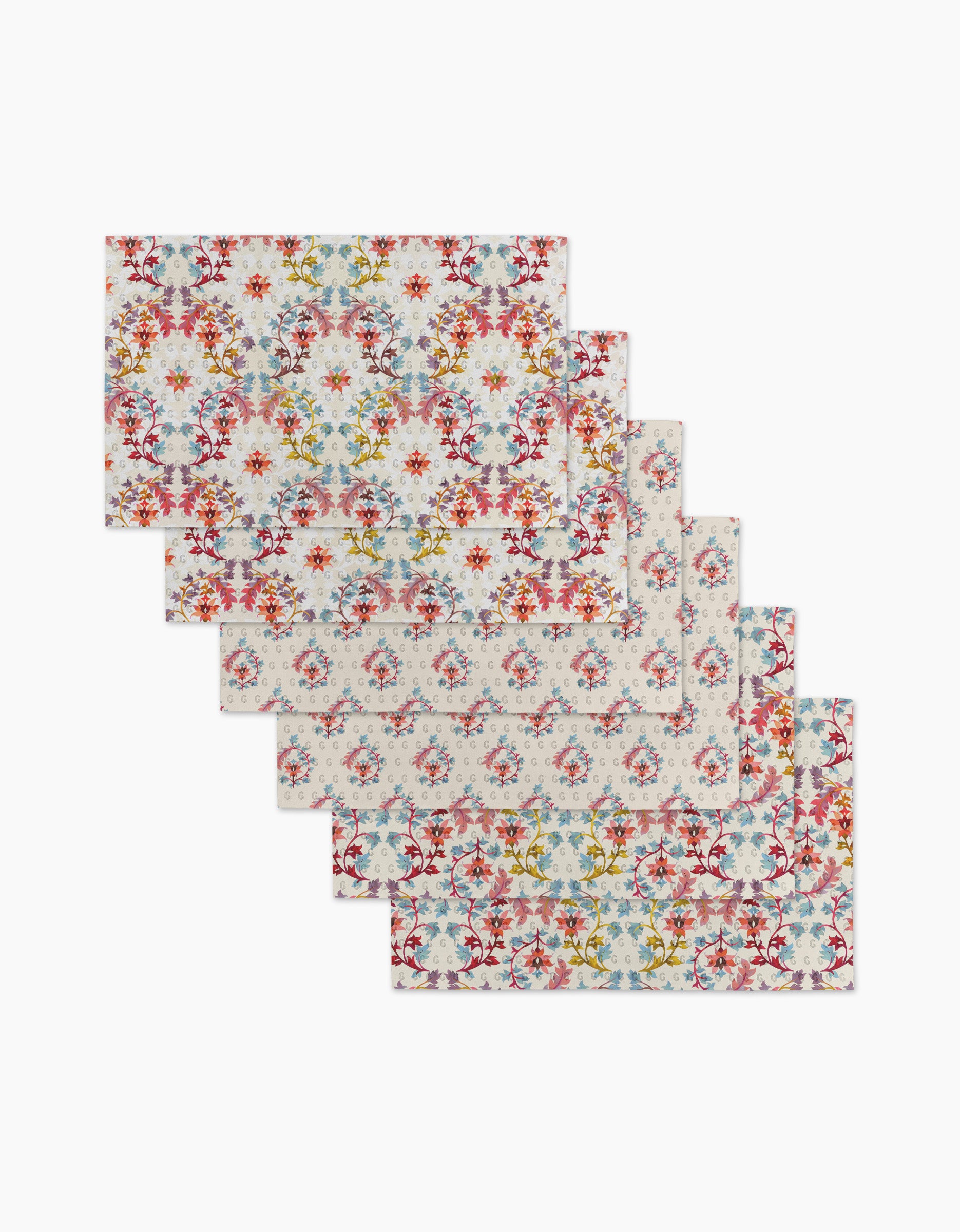 Six Folk Medallion placemats by Maayan Alper-Swan, featuring a colorful floral pattern on a light background, are fanned out—ideal to pair with eco-friendly paper towels for a sustainable table setting.