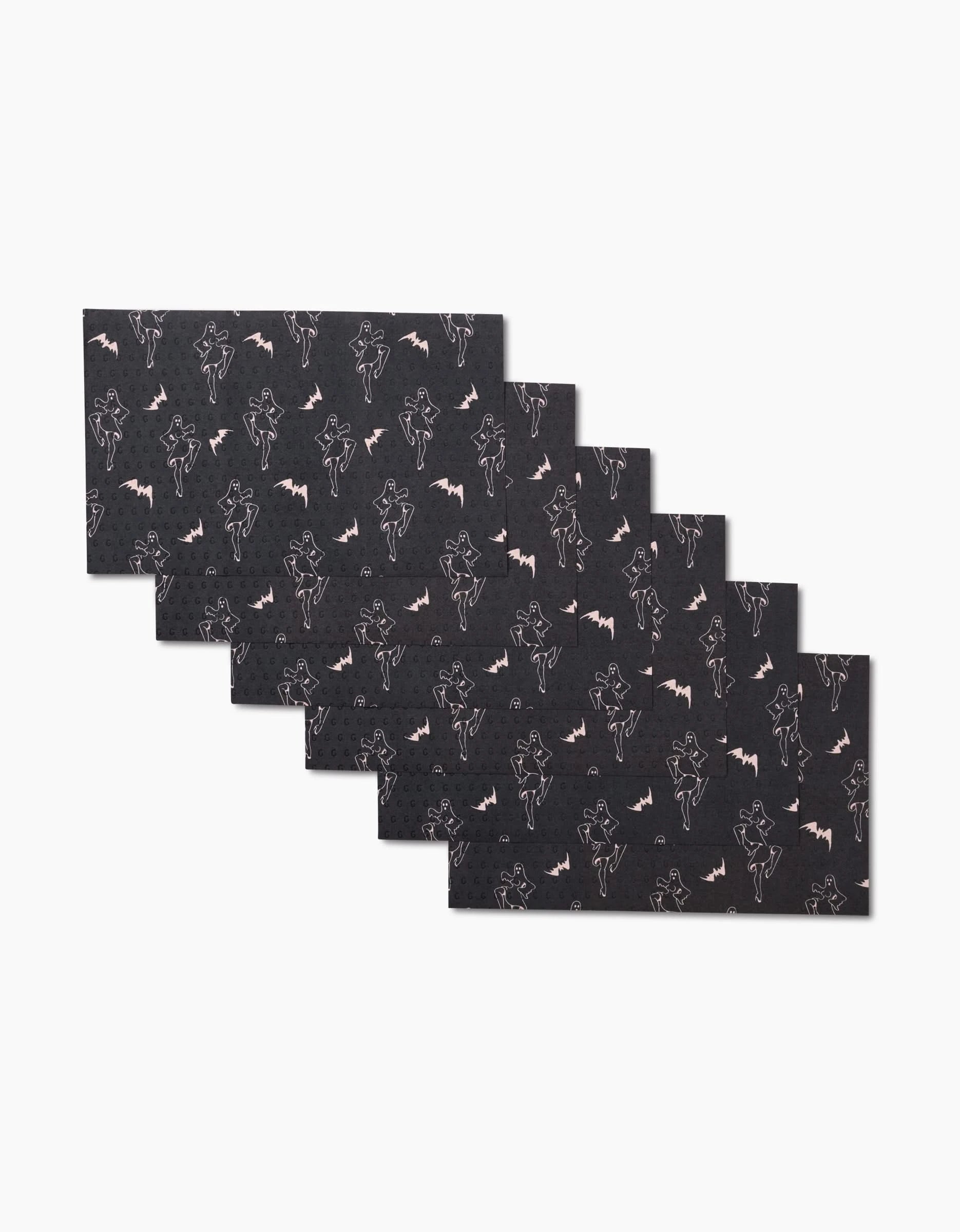 Six rectangular black Ghost Pin Up placemats by Cole Strem are stacked in a staggered pile. Each reusable placemat features a white outline pattern of bats and vampire-like figures on a plain white background.