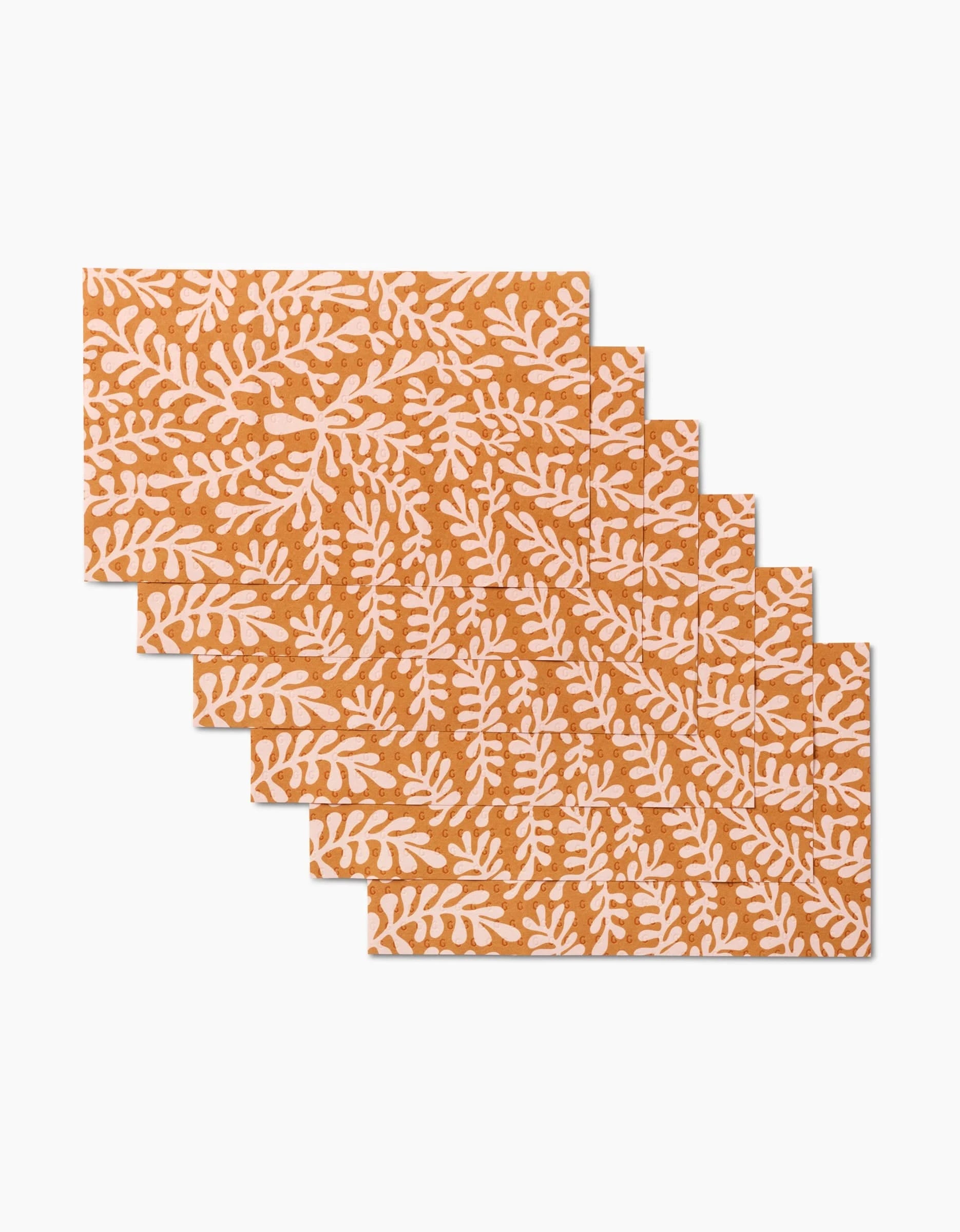 Six GEOMETRY Golden Fall rectangular napkins, featuring a brown-orange background with white botanical leaf motifs, are arranged in an overlapping fan pattern as a stylish, eco-friendly alternative to Not Paper Towels.