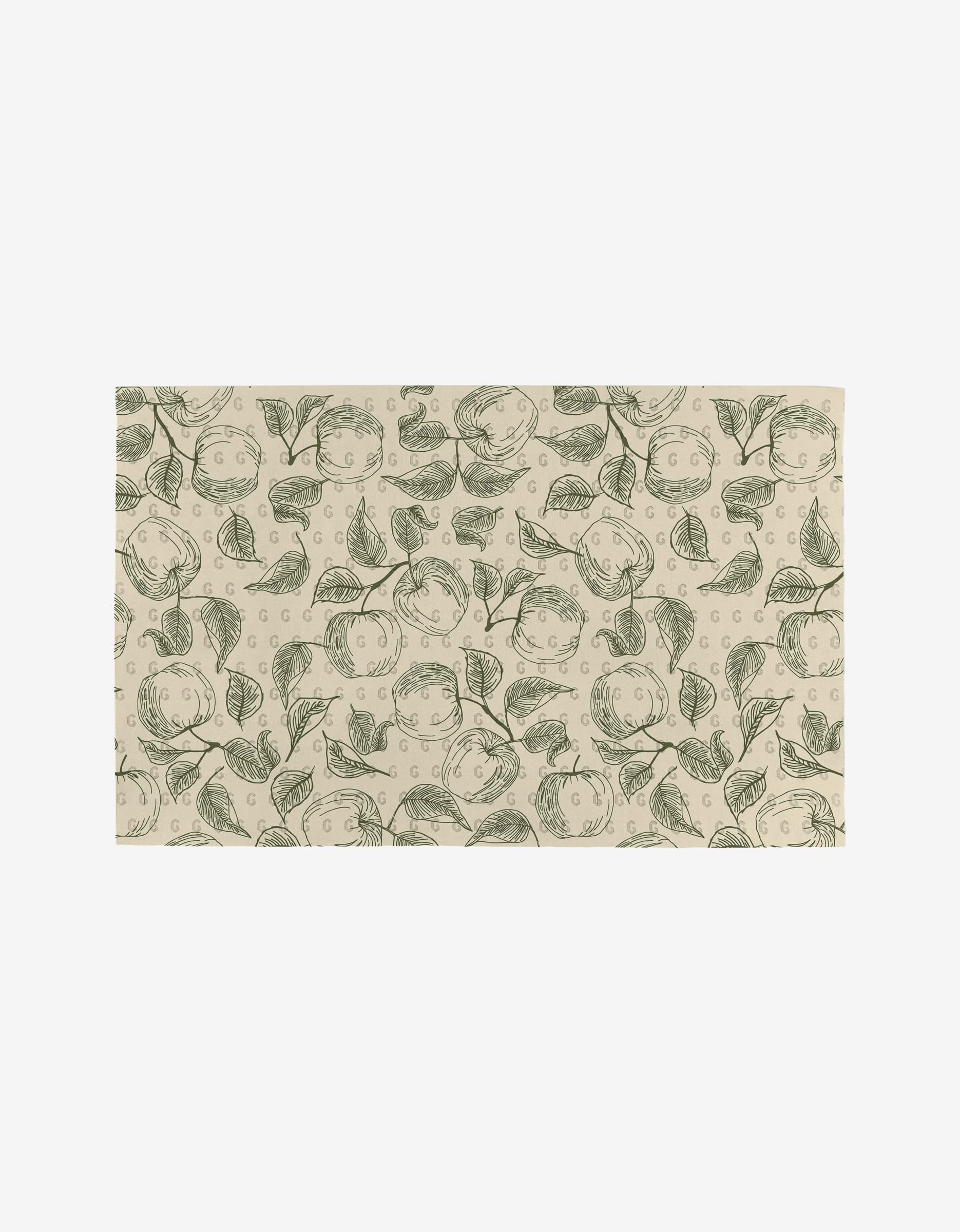 A rectangular beige mat by Ash Cascade, the Gravenstein Apple features a repeating pattern of green outlined apples and leaves. Crafted from post-consumer recycled materials, it’s an eco-friendly alternative inspired by Not Paper Towels.