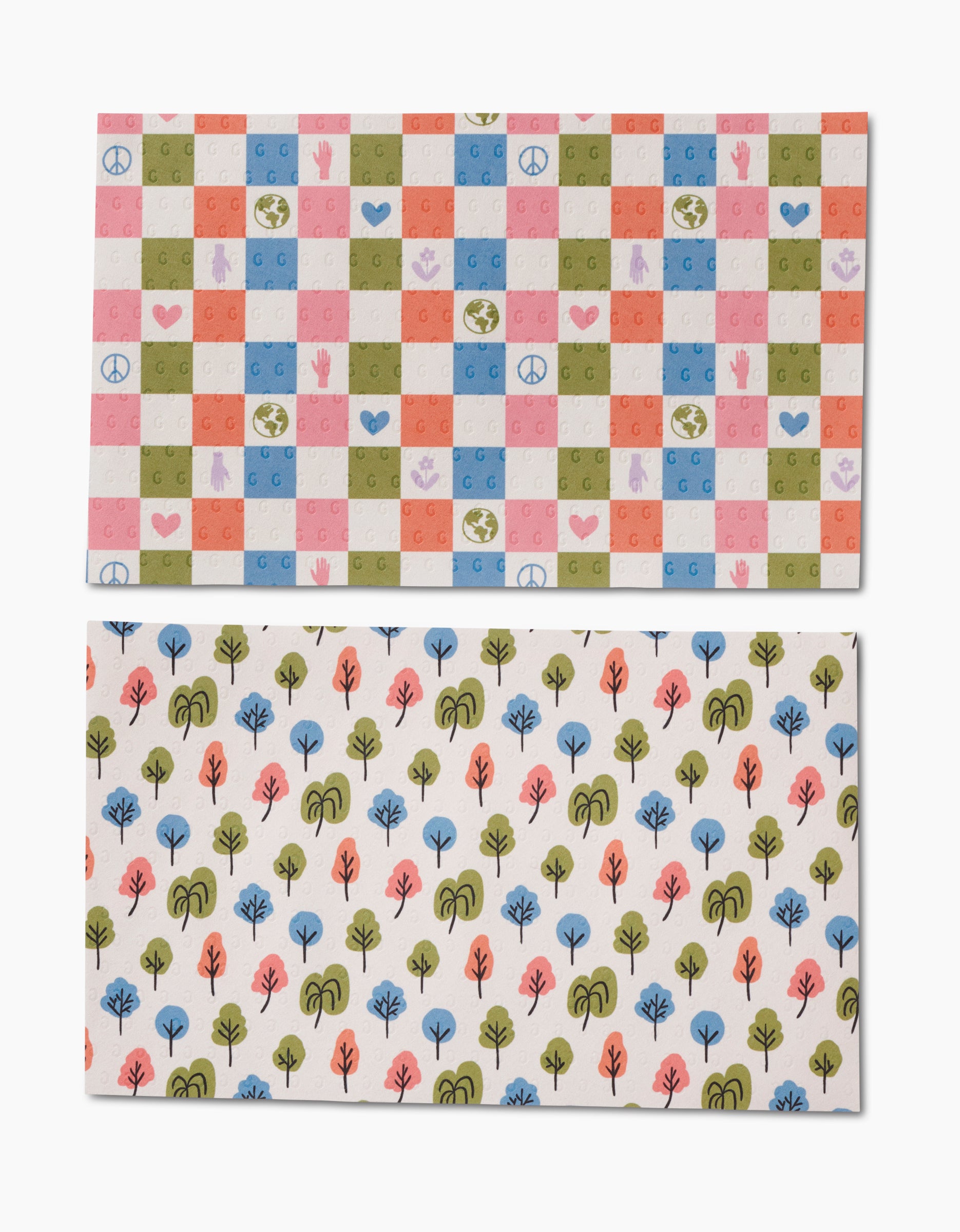 Kayla Anns Happy Checkers Not Paper Towels feature two rectangular sheets: the top displays peace signs, hearts, globes, and hands in a checkerboard; the bottom has colorful trees. Made with post-consumer recycled materials.