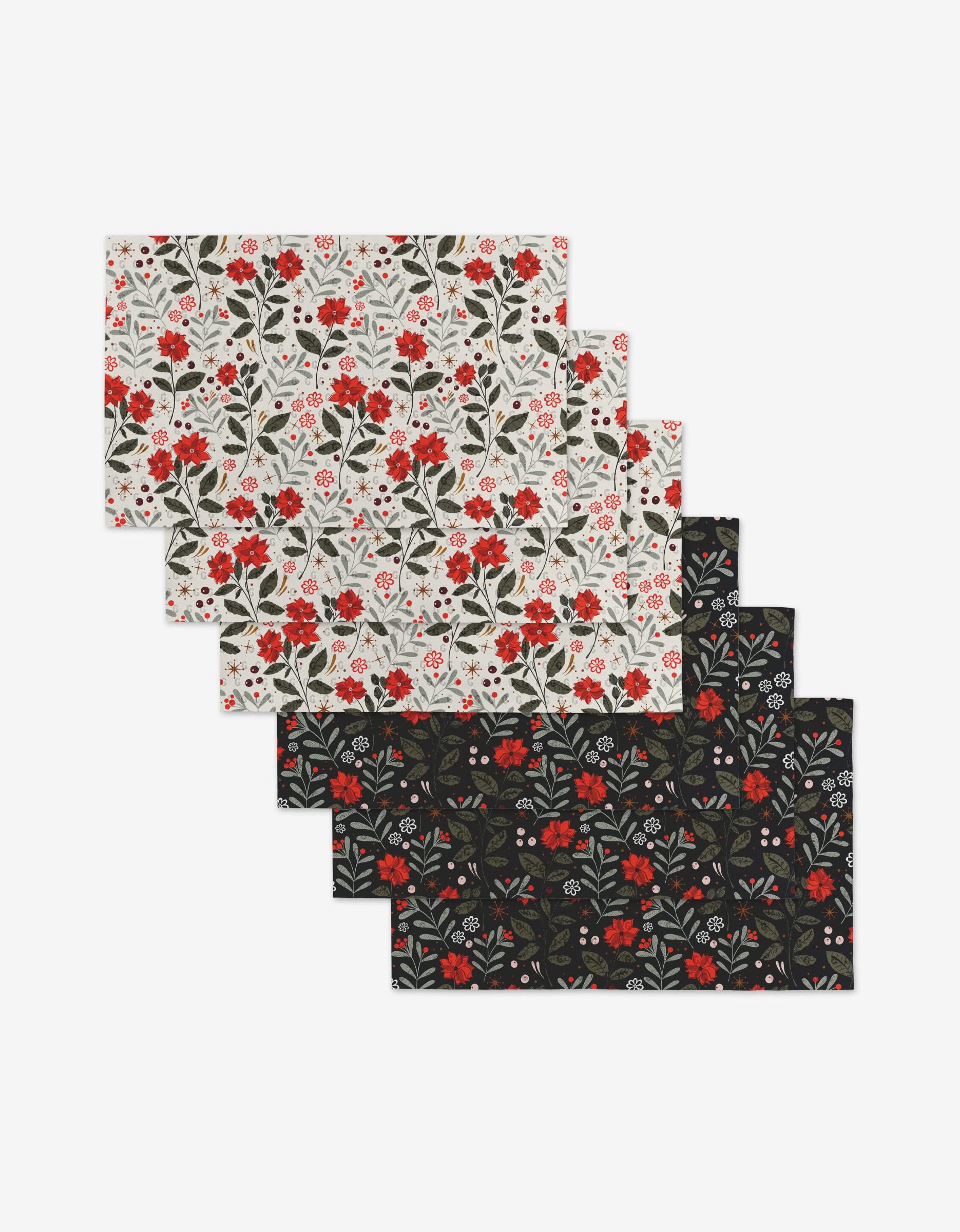 The Holiday Floral set by Charlie Rowan Designs includes six reusable rectangular placemats—three white, three black—all with red, white, and green floral patterns. An eco-friendly alternative to Not Paper Towels.