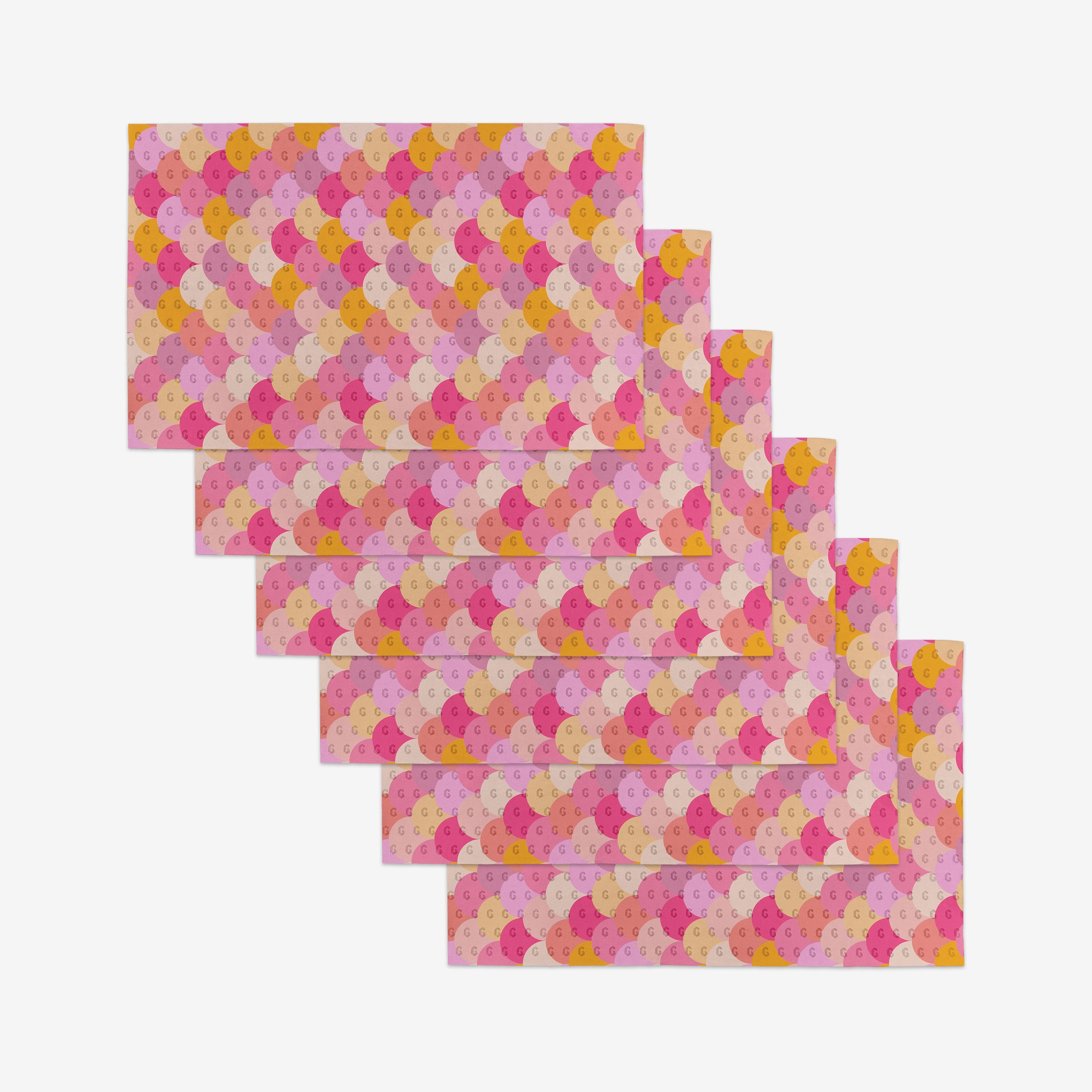 Six rectangular pieces from GEOMETRY’s Inherit line, made of eco-friendly recycled materials, feature repeating pink, yellow, orange, and red semi-circles and are stacked in a staggered arrangement on a white background.