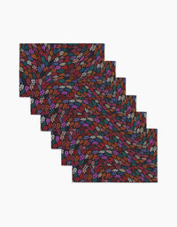 The Jewel Leaf Swirl placemat set by Rachel Parker includes six rectangular mats with a colorful leaf-like pattern in red, orange, purple, blue, and white on a dark background, arranged in an overlapping layout on a white surface.