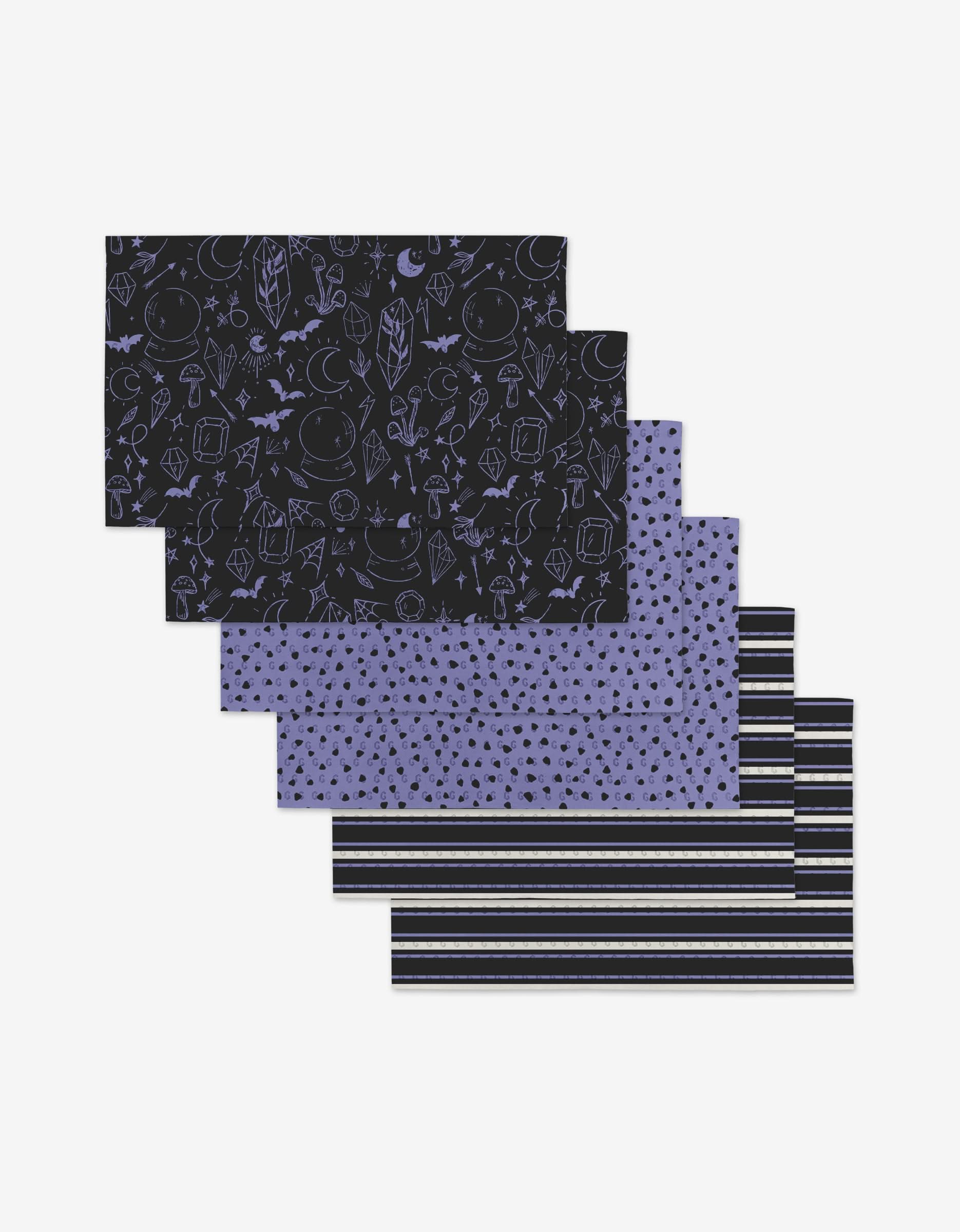 Six Magic Spells Not Paper Towels by Hufton Studio are stacked, showcasing various black and purple patterns—space doodles, stars, and stripes. Made from eco-friendly materials.