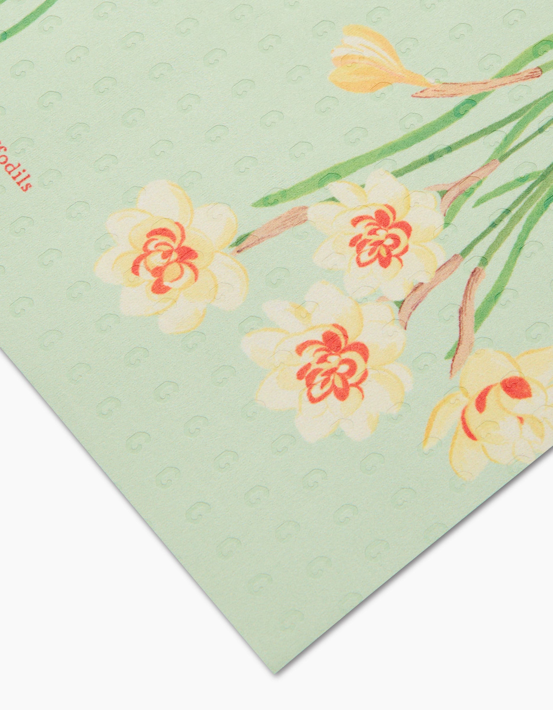 A close-up of March Daffodils by Linda Fox shows pale yellow and orange daffodil illustrations on light green textured, post-consumer recycled paper, with a corner of the sheet in view.