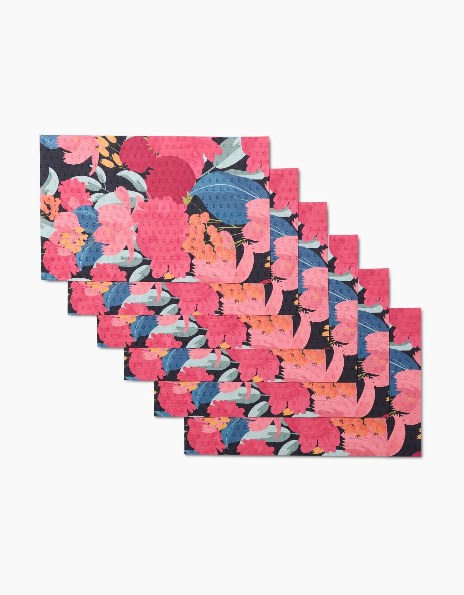 Eight reusable GEOMETRY My Garden placemats featuring a vibrant floral pattern in pink, coral, blue, and green on a dark background, shown overlapping in a staggered display.